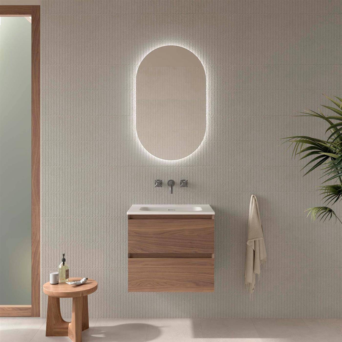 Modernes Minimalbadezimmer mit schwebendem Holzwaschtisch, ovalem hinterleuchtetem Spiegel, Handtuch und einem kleinen Beistelltisch neben einem raumhohen Spiegel.