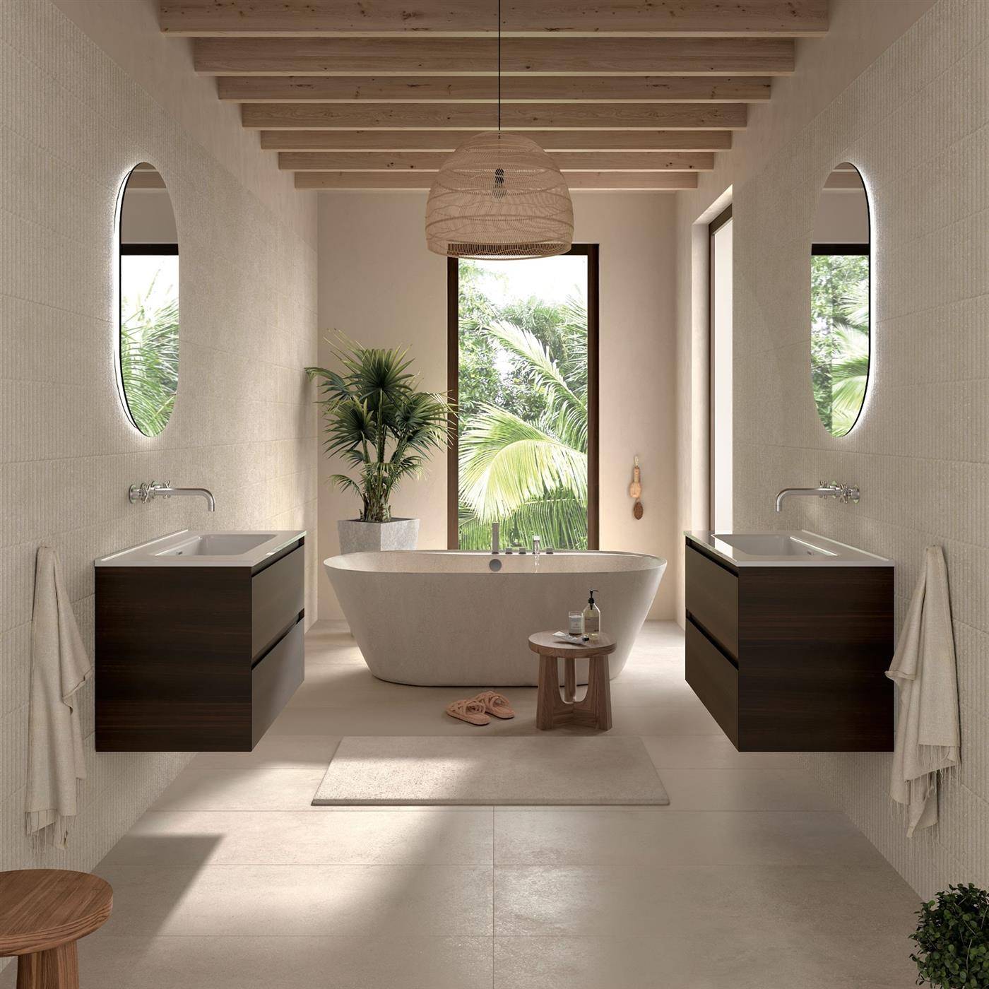 Modernes Badezimmer mit einer freistehenden Badewanne, die zwischen zwei dunklen Waschtischen zentriert ist, ovalen Spiegeln und einem großen Fenster mit Palmen außen.