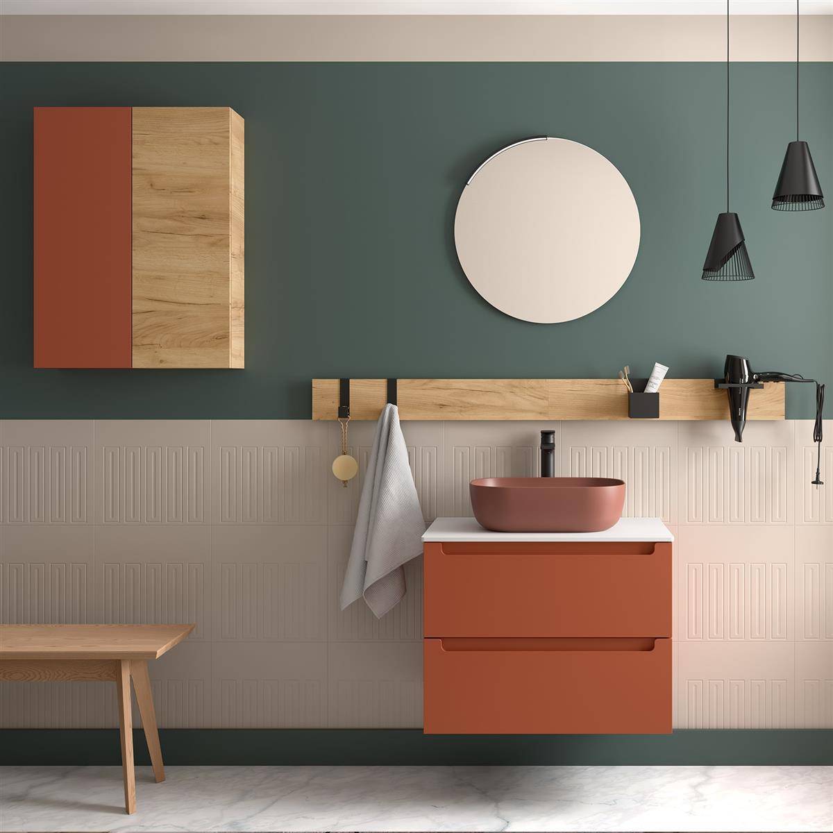 Modernes Badezimmermöbel mit Terrakotta-Schrank und Aufsatzwaschbecken vor grüner und beigefarbener Wand, mit rundem Spiegel, Regal, hängendem Handtuch und Pendelleuchten.