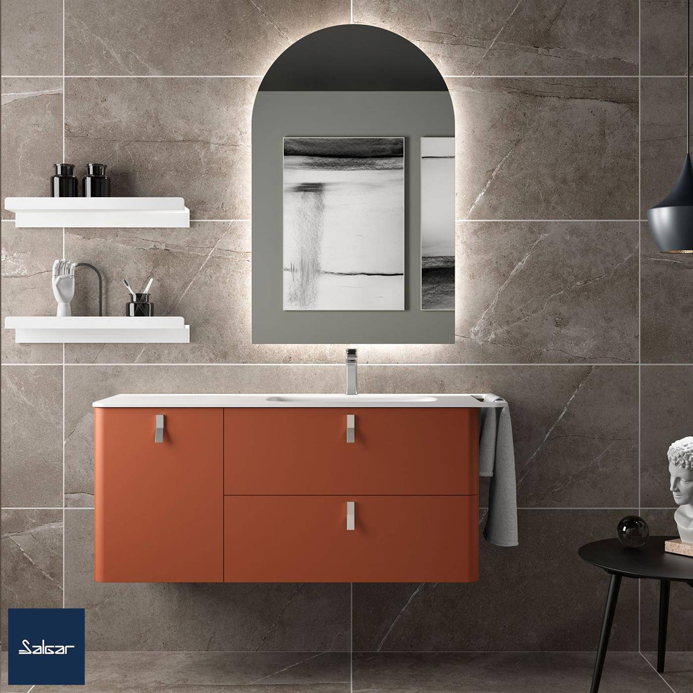 Modernes Badezimmer mit an der Wand befestigter orangefarbener Waschtischanlage, gewölbtem Spiegel, Regalen und grauen Fliesenwänden; kleiner Beistelltisch und Wandkunst sichtbar.