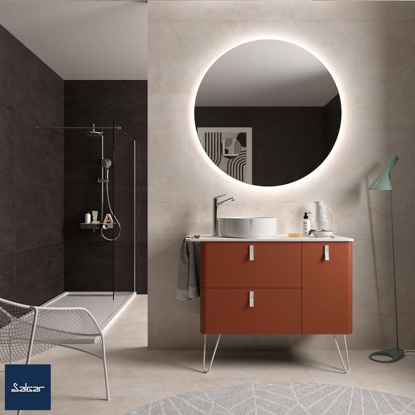 Modernes Badezimmer mit einem runden hintergrundbeleuchteten Spiegel über einer terrakottafarbenen Waschtischplatte, einer begehbaren Dusche auf der linken Seite und einer Stehleuchte neben dem Waschbecken.