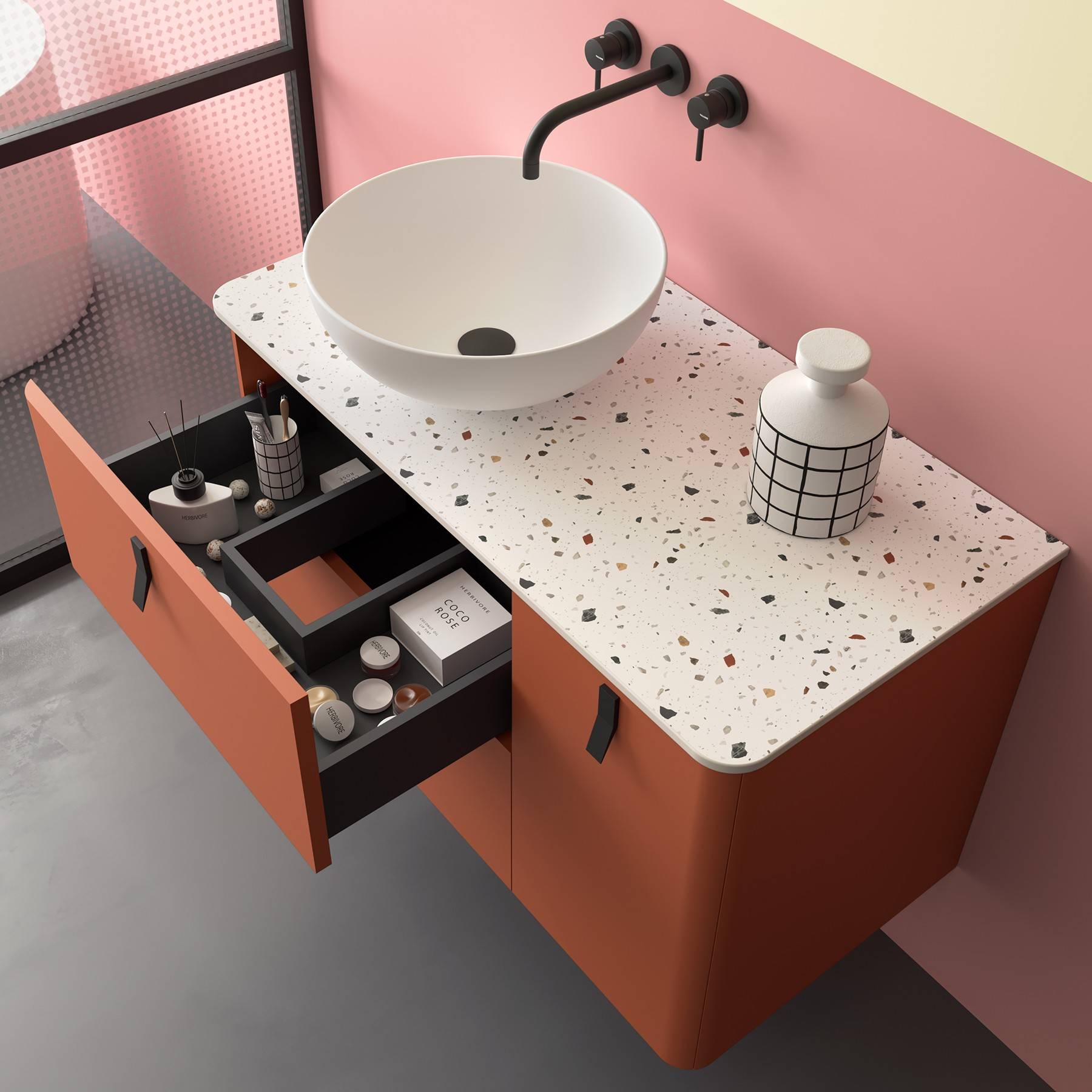 Moderne Badezimmerkommode mit einer Terrazzo-Arbeitsplatte, rundem Waschbecken und geöffneter Schublade, die ordentlich angeordnete Toilettenartikel und eine geometrische Vase offenbart.