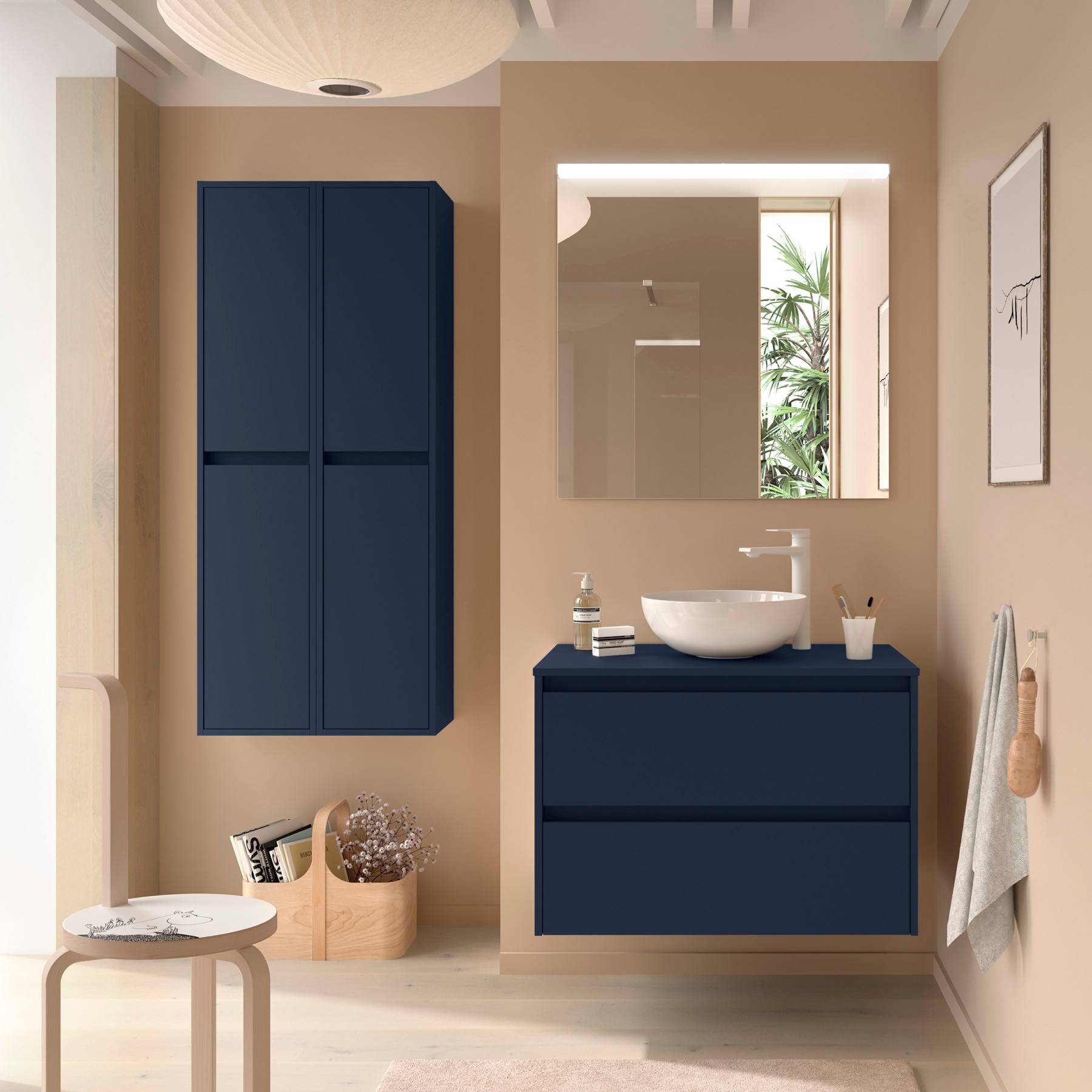 Ein modernes Badezimmer mit einer marineblau-Waschtischplatte und einem marineblau-Wandschrank, beigen Wänden, einem runden Spiegel und minimalistischer Dekoration, einschließlich eines kleinen Tisches und Handtücher.