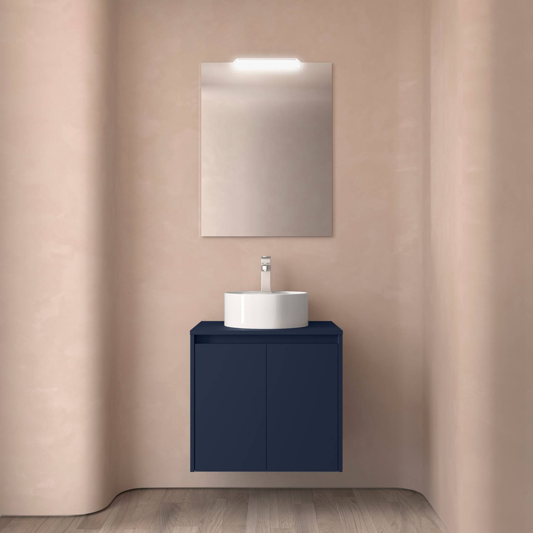 Ein minimalistisches Badezimmer präsentiert eine beige Wand, einen rechteckigen Spiegel mit Beleuchtung und einen blauen Waschtisch mit einem weißen runden Waschbecken und Wasserhahn.