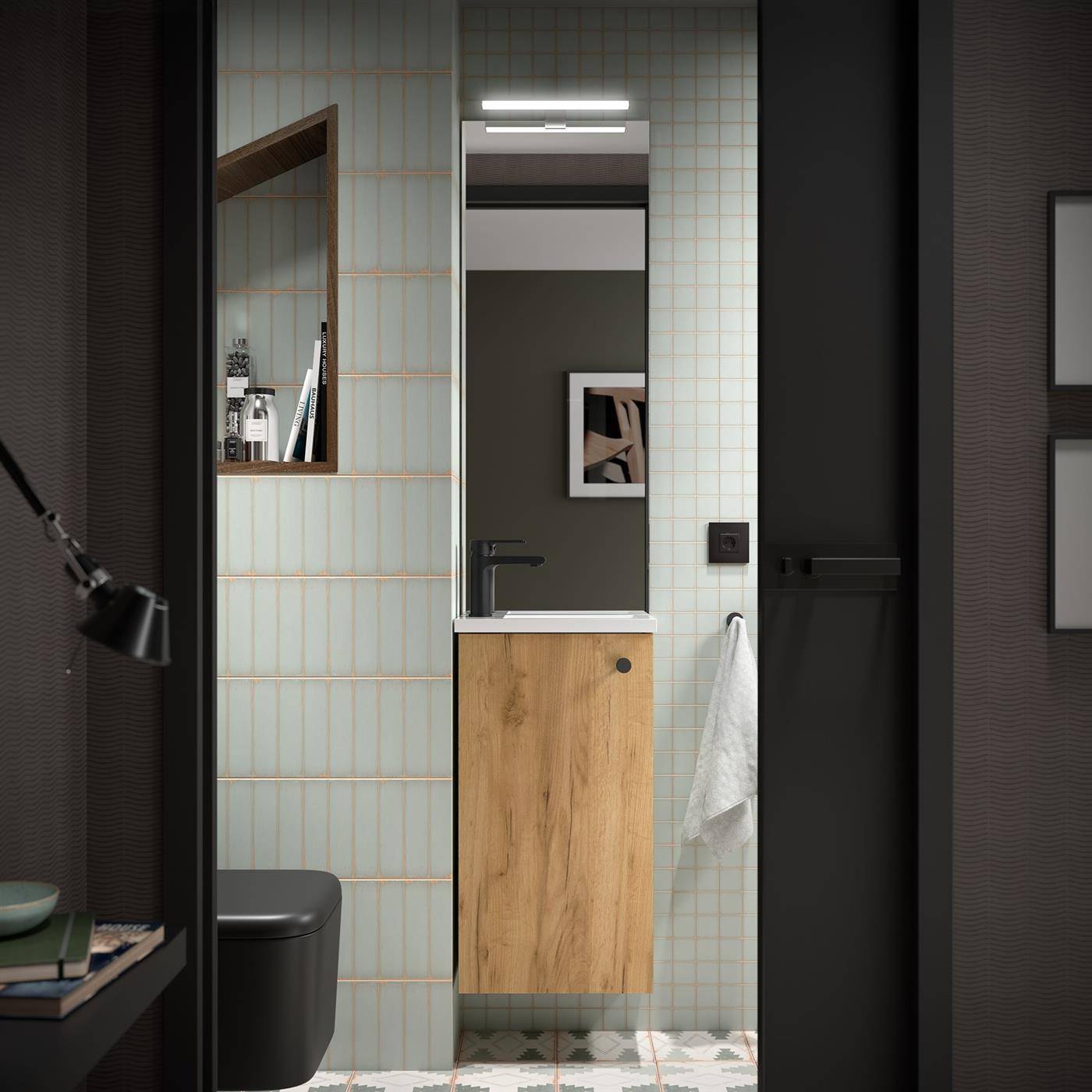 Modernes Badezimmerwaschtisch mit Spiegel, Wandleuchte, weiß geflieste Wände, Holzschrank, schwarze Toilette und Handtuch an einer dunklen Tür.