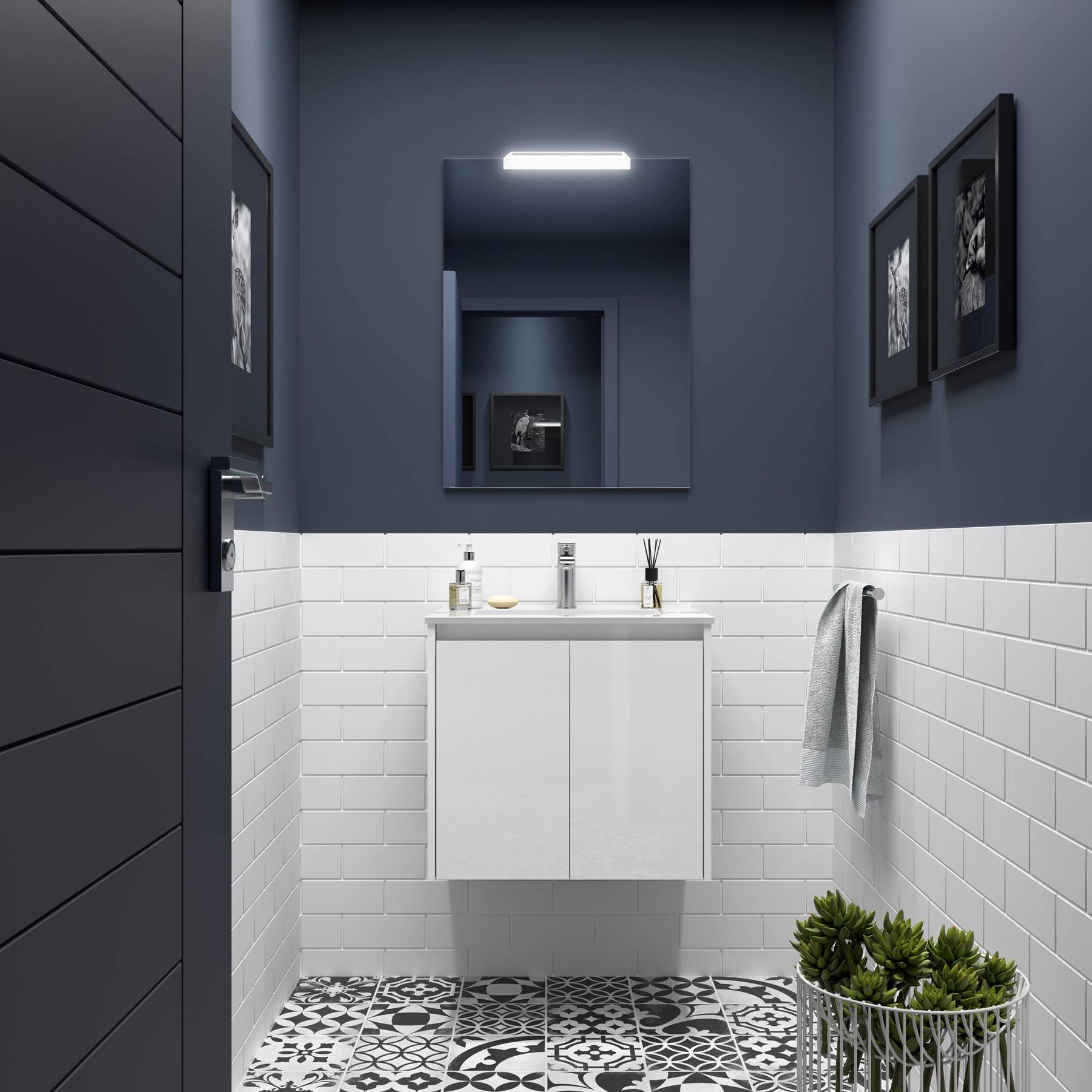 Ein kleines, modernes Badezimmer mit dunklen Wänden, weißen Metrofliesen, einem gemusterten Boden, einem Spiegel und gerahmten Fotos an der Wand.