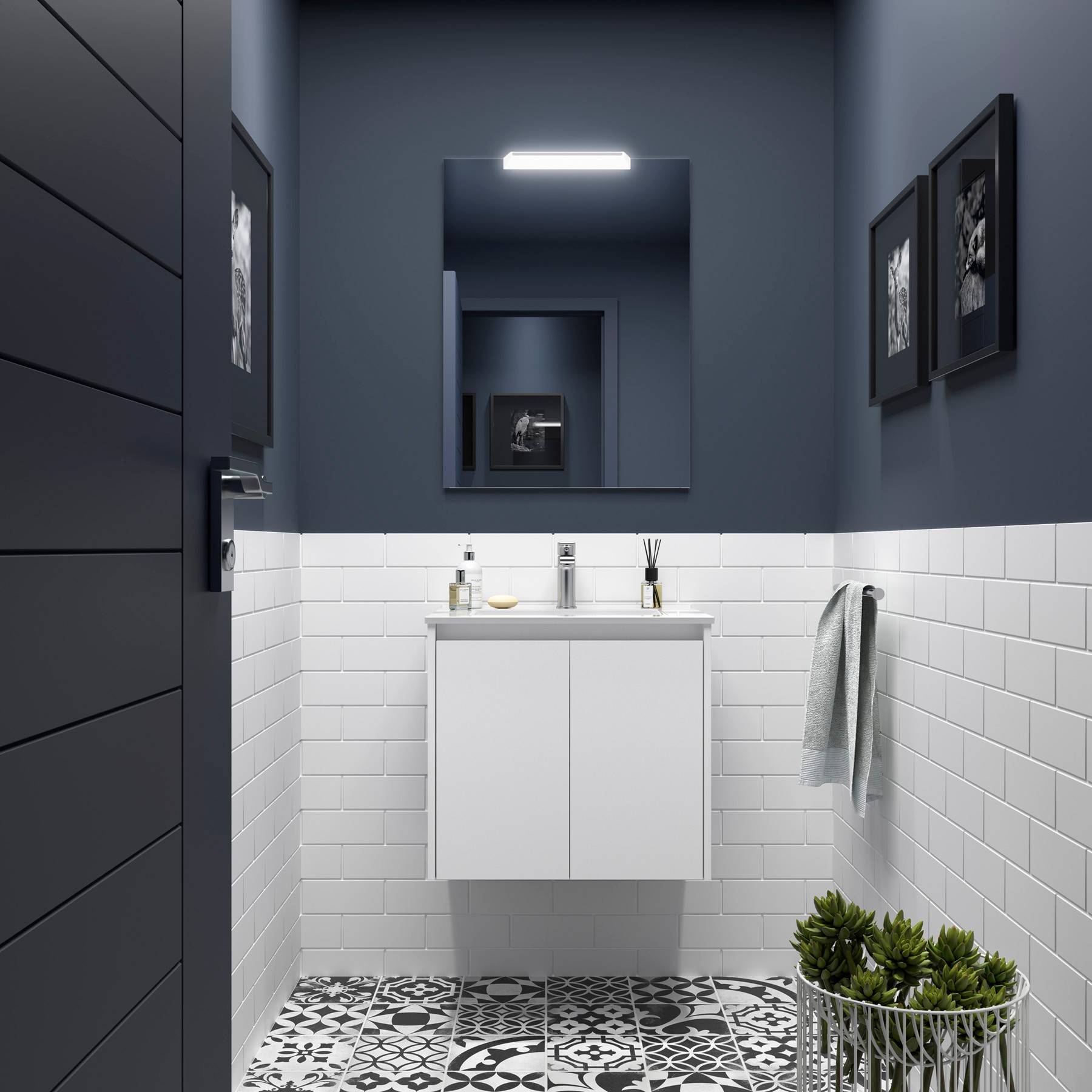 Ein modernes Badezimmer mit dunklen Wänden, einer weißen gefliesten unteren Hälfte, einem weißen Waschtisch mit Waschbecken, einem Spiegel, einer kleinen Pflanze und gerahmten Bildern.