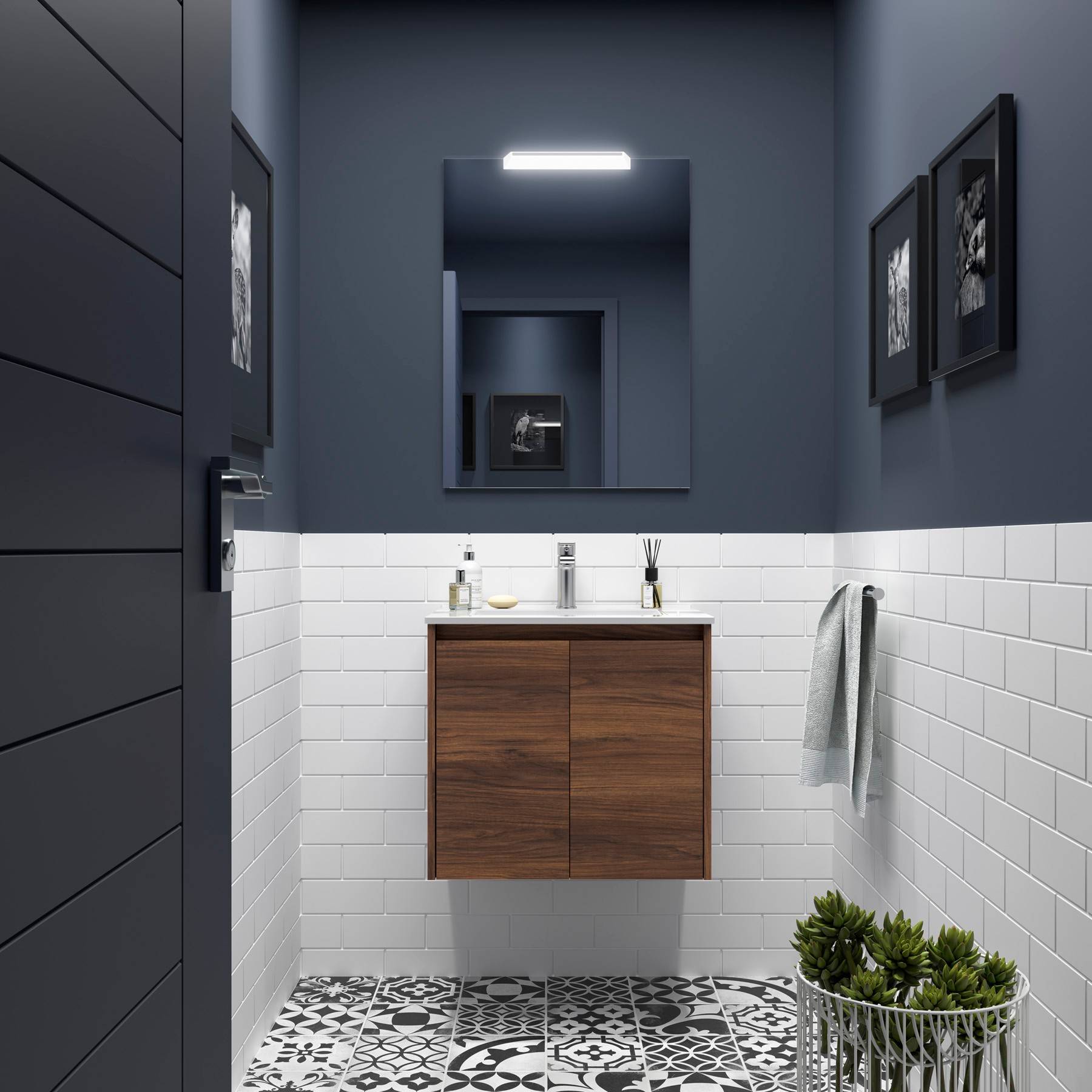 Modernes Badezimmer mit einem Waschtisch aus Holz, einem Spiegel und Bodenfliesen mit Muster. Weiße U-Bahn-Fliesen bedecken die Wände zur Hälfte. An der Wand hängen gerahmte Bilder.