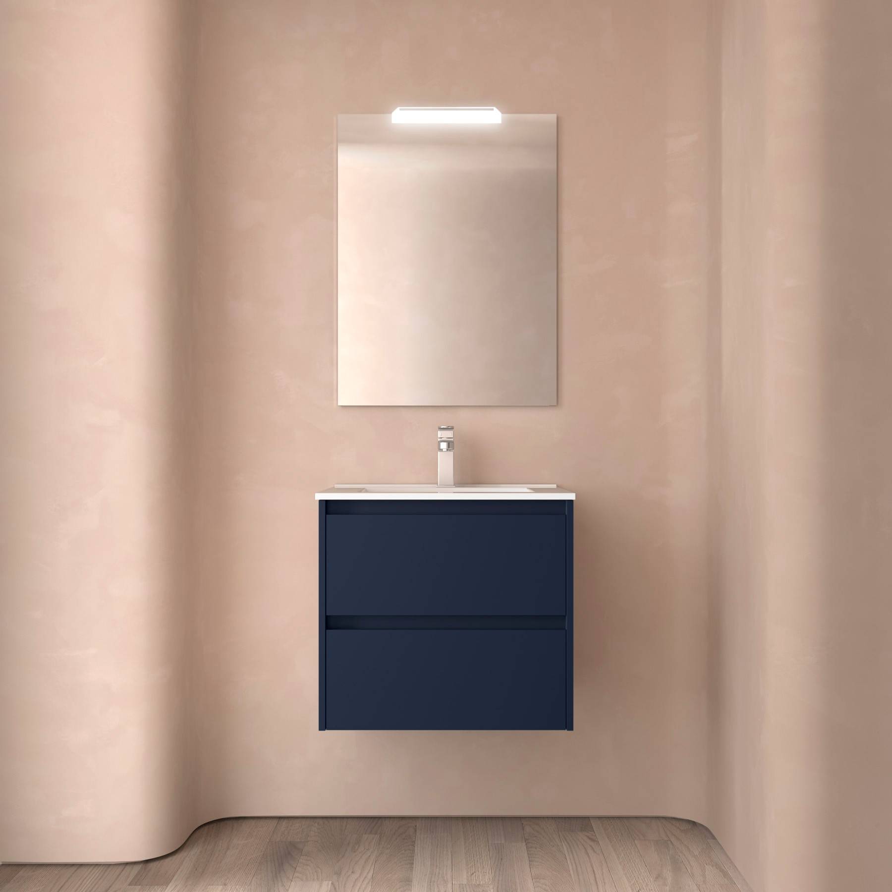 Ein minimalistisches Badezimmer mit einem wandmontierten blauen Waschtisch, einem rechteckigen Spiegel darüber und einem sanften Licht von oben, vor beigen Wänden.