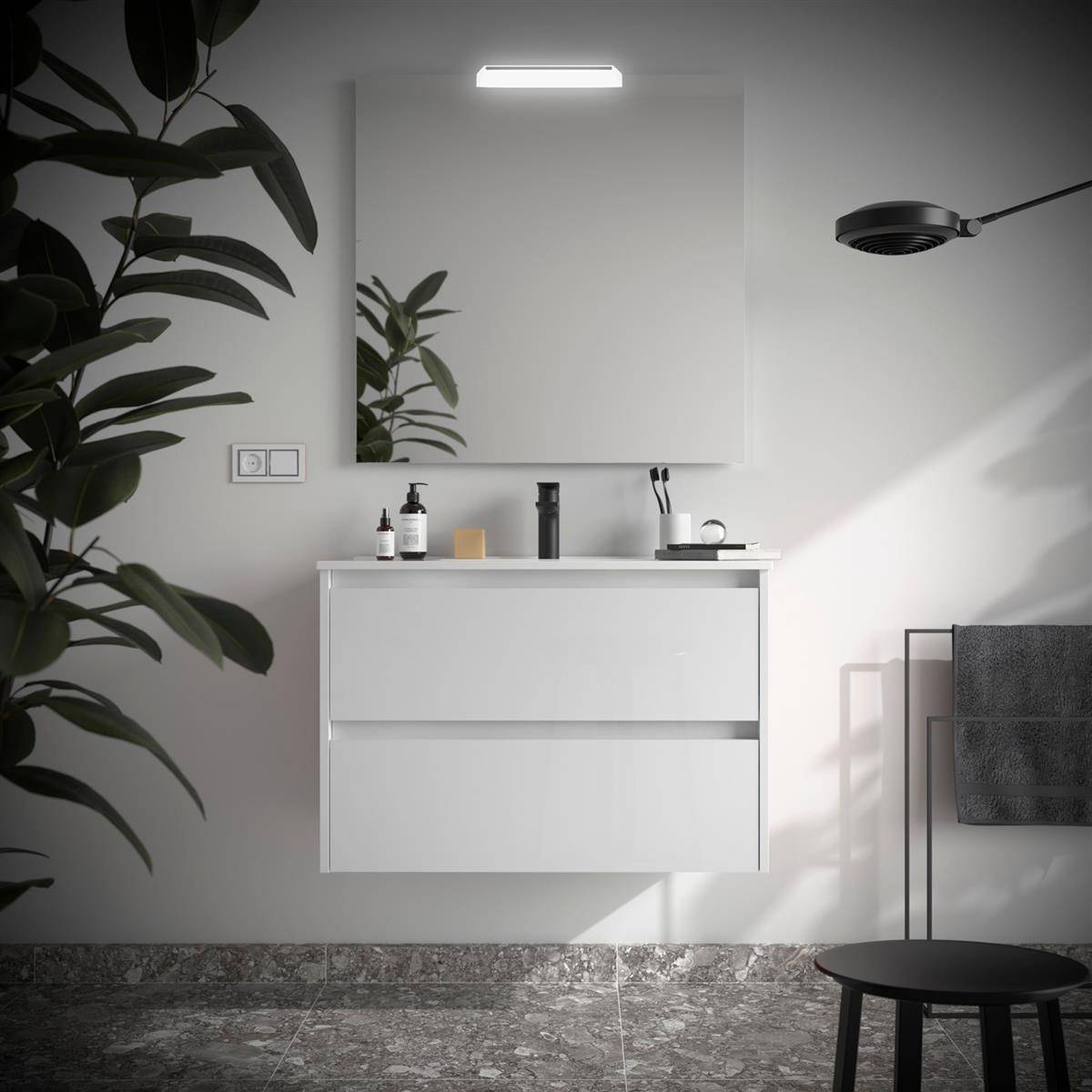 Minimalistisches Badezimmer mit schwebendem weißem Waschtisch, Spiegel, Wandleuchte, Spülbeckenzubehör, Handtuchhalter und schwarzem Hocker neben einer großen Pflanze.