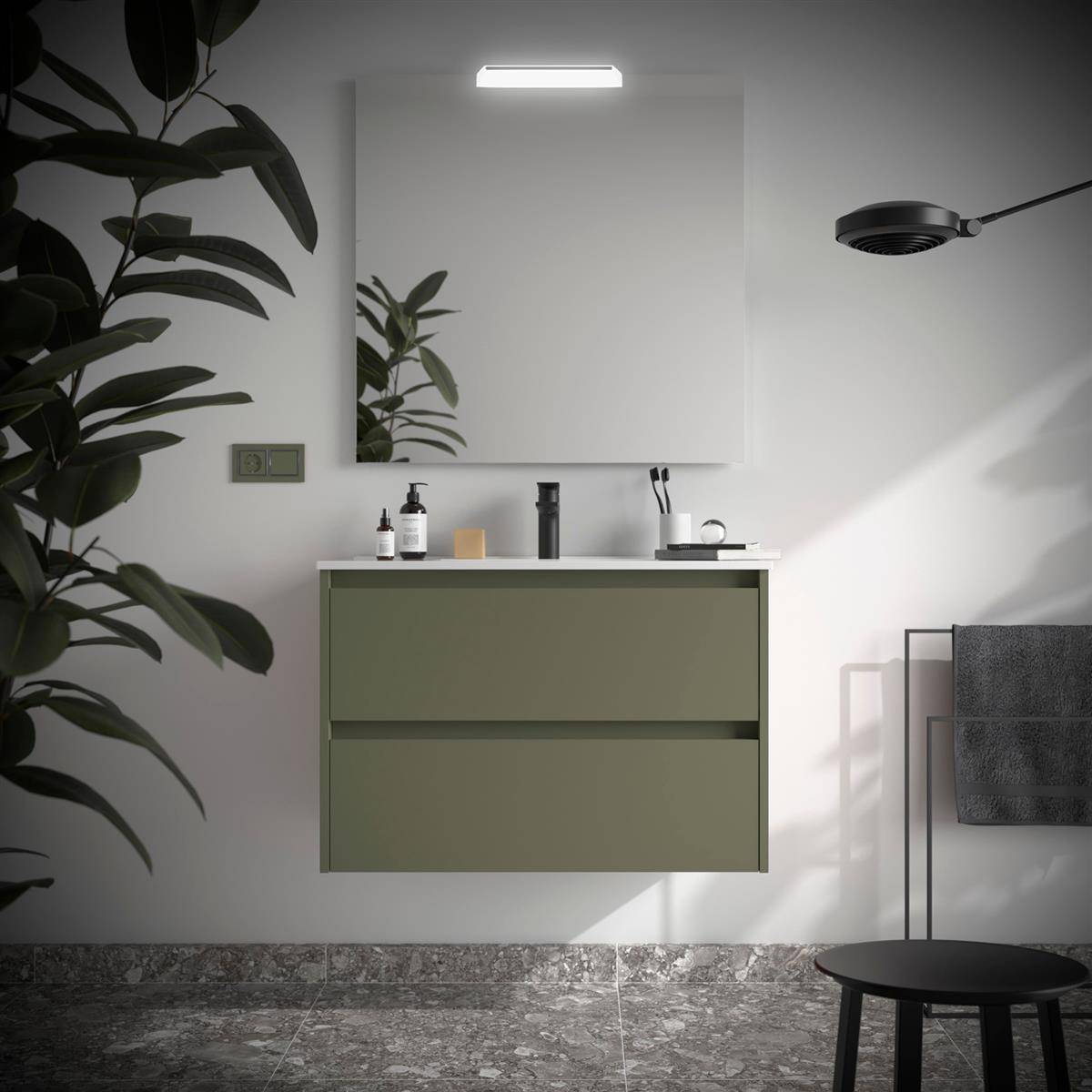 Minimalistisches Badezimmer mit wandmontiertem olivgrünem Waschtisch, Spiegel, Leuchte, Waschbecken-Accessoires, Handtuchhalter, Hocker und großer Blattpflanze.