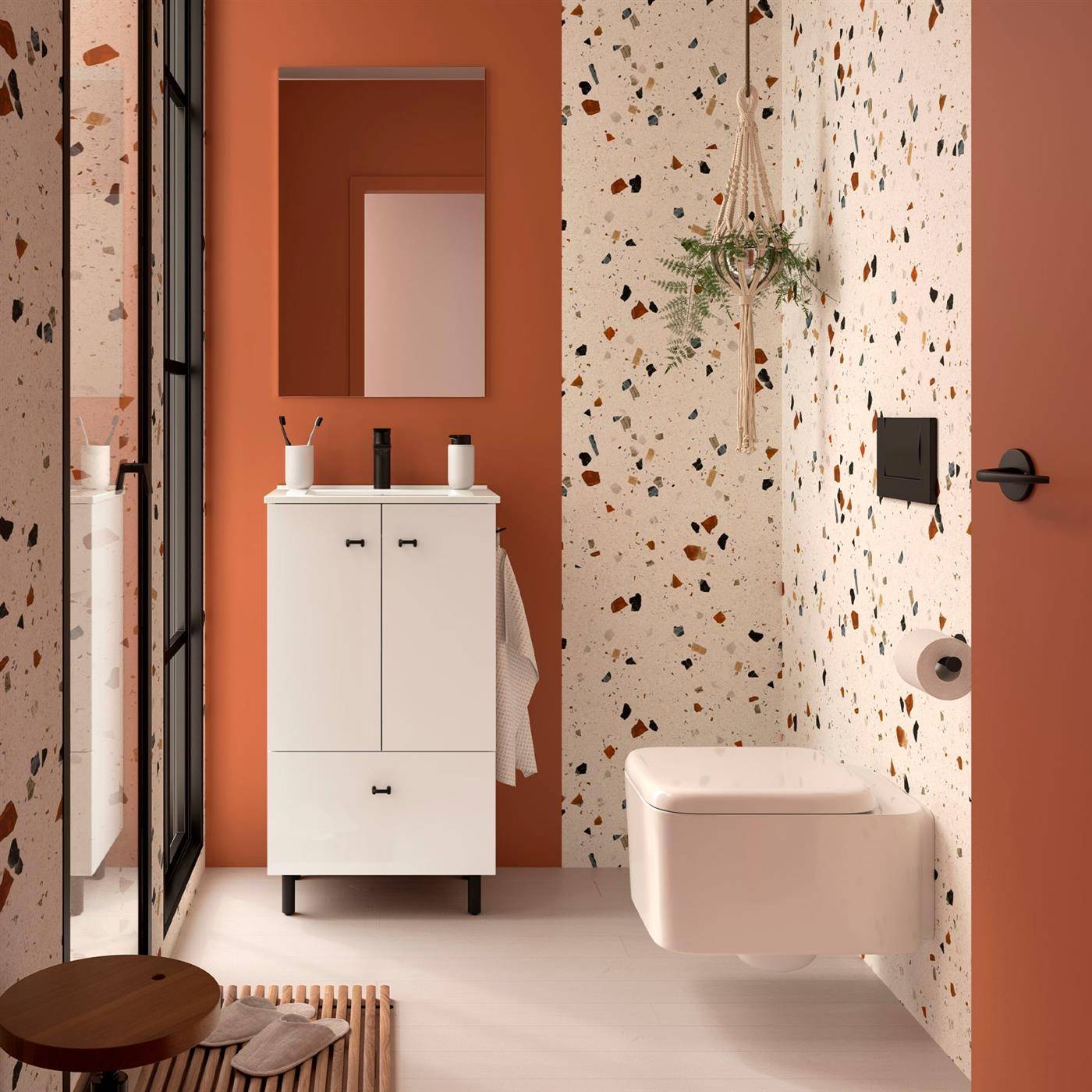 Modernes Badezimmer mit Terrazzo-Tapete, an der Wand montierter Toilette, weißem Waschtisch, Spiegel und schwarzer Rahmenduschtür in einem warmen Terrakotta-Raum.