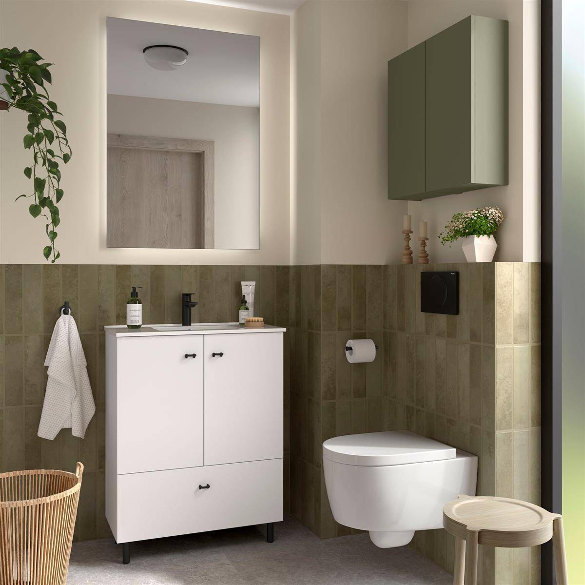 Modernes Badezimmer mit an der Wand montierter Toilette, weißem Waschtisch und Spiegel, olivgrüner Fliesenverkleidung und kleinem Wandschrank; ein Weidenkorb steht in der Nähe.