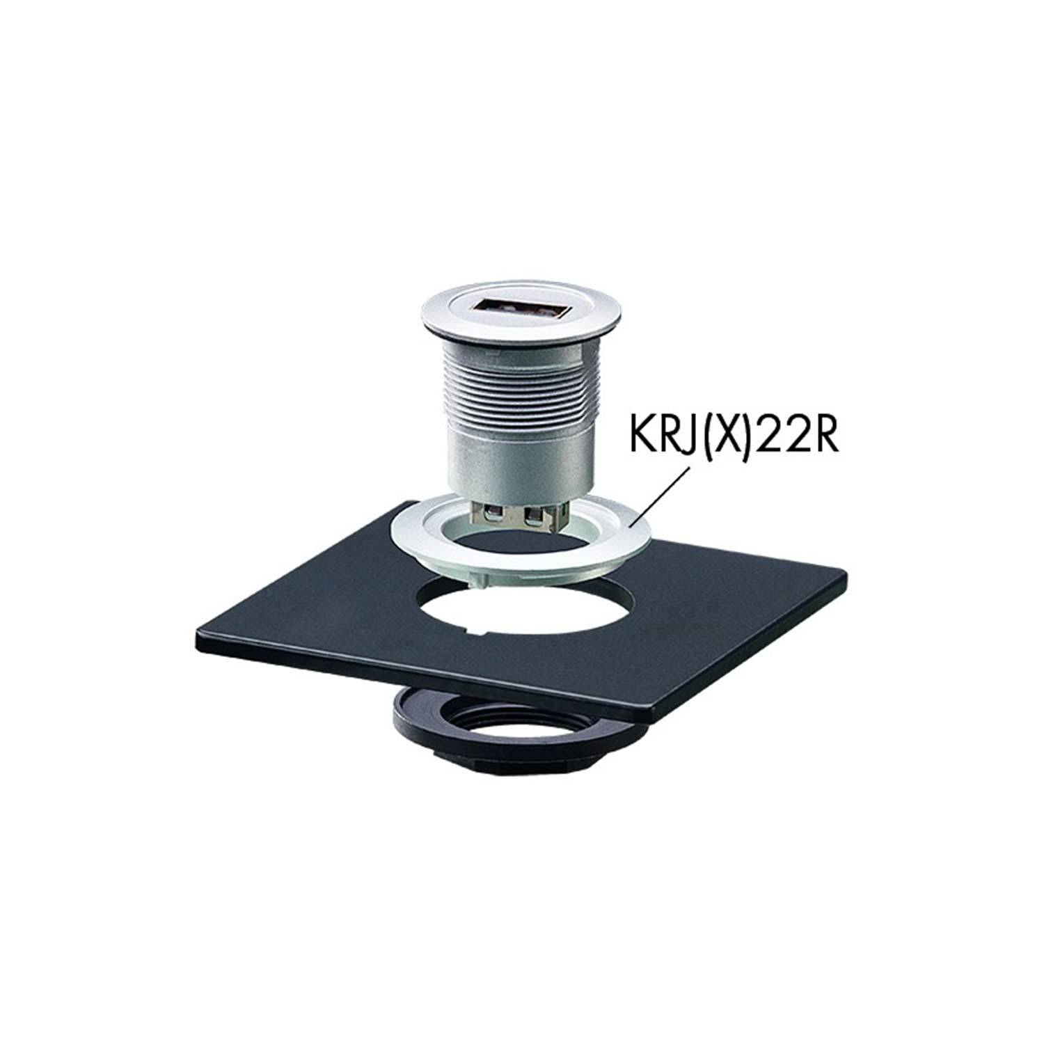 Eine kleine Metallkomponente mit der Beschriftung KRJ(X)22R ist über einem schwarzen Gehäuse mit einer kreisförmigen Öffnung zu sehen, was auf eine vorgesehene Montage oder Passung hindeutet.