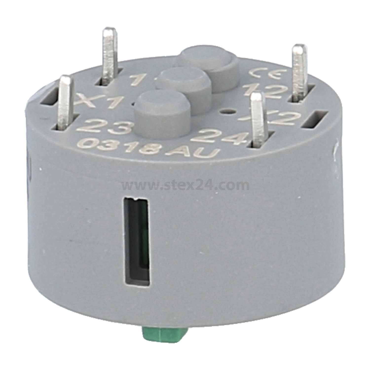 „Eine graue, kreisförmige elektrische Komponente mit mehreren Metallstiften, die von oben und den Seiten herausragen, beschriftet mit Zahlen und Buchstaben.