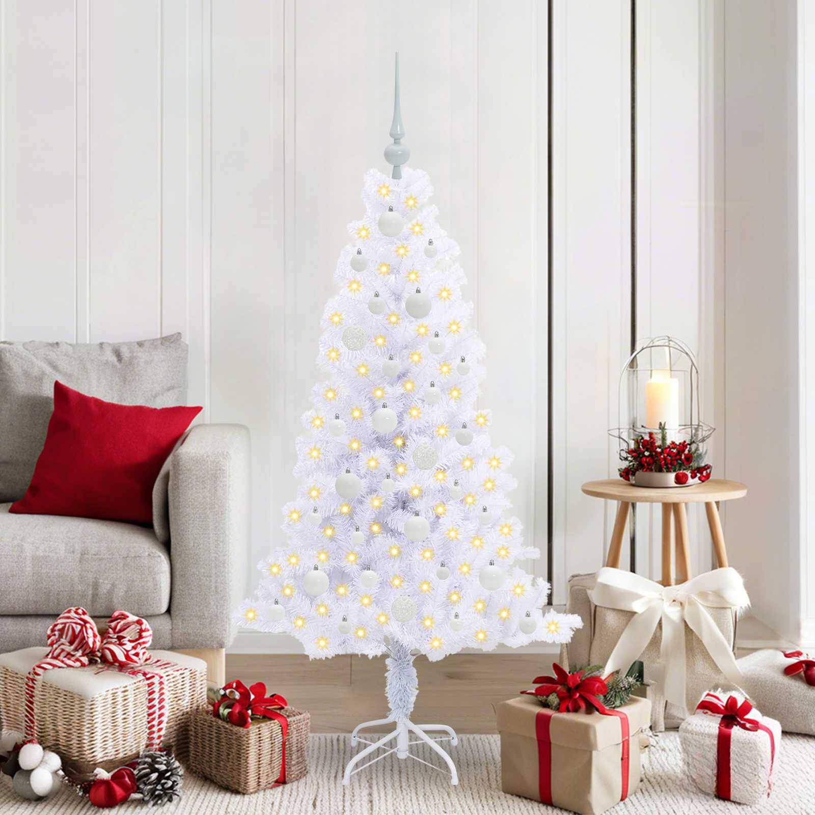 Ein weißer Weihnachtsbaum mit leuchtenden Lichtern steht in einem gemütlichen Raum, geschmückt mit Geschenken und kerzenbeleuchtetem Dekor auf einem Holzseitentisch.