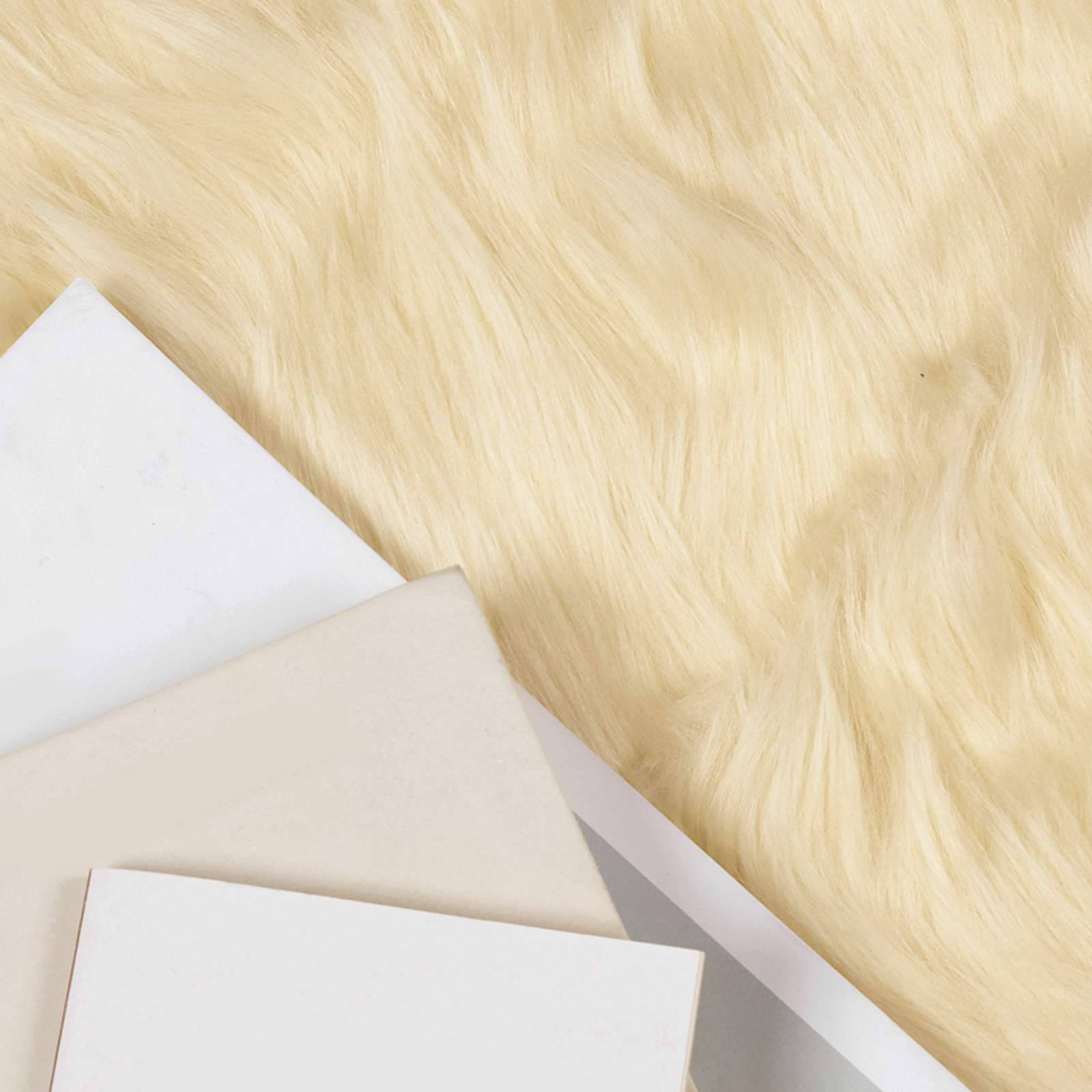 Drei überlappende Blätter Papier, jedes in einem anderen Ton von Weiß und Beige, vor einem flauschigen cremefarbenen Hintergrund.