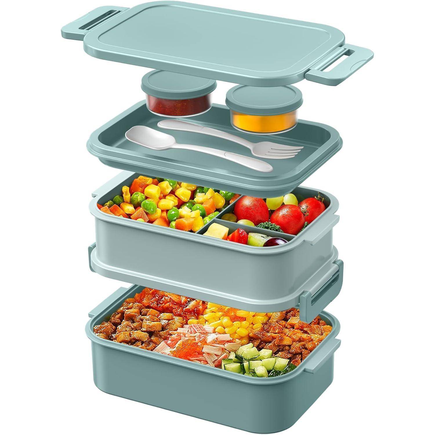 Eine stapelbare Lunchbox mit zwei Ebenen. Die obere Ebene enthält eine Gabel, einen Löffel und zwei kleine Behälter; die untere Ebene enthält verschiedene Gemüsesorten und Fleischsorten.