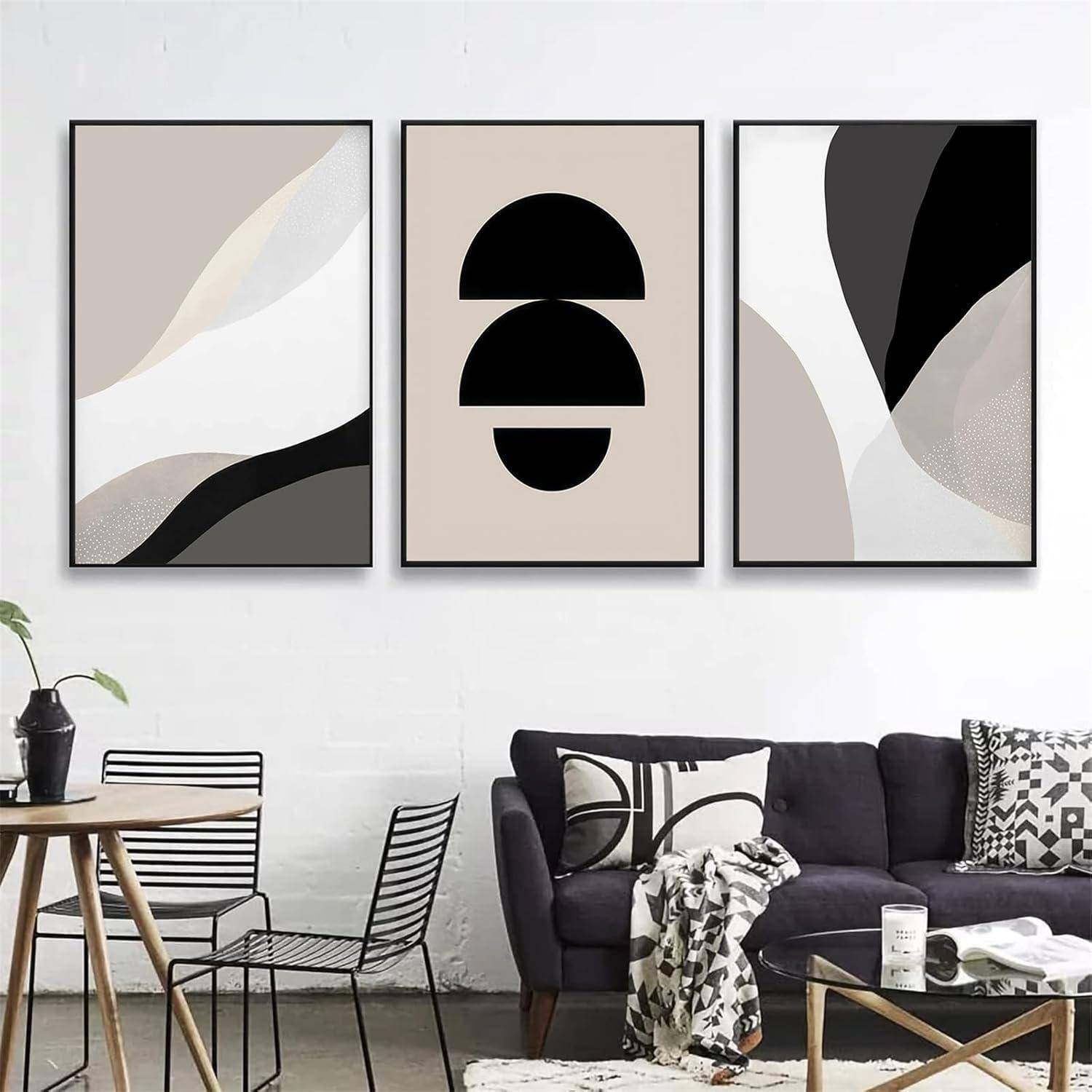 Drei abstrakte Kunstwerke mit geometrischen Formen und neutralen Farbtönen hängen an einer weißen Wand über einem modernen schwarzen Sofa und Tisch.