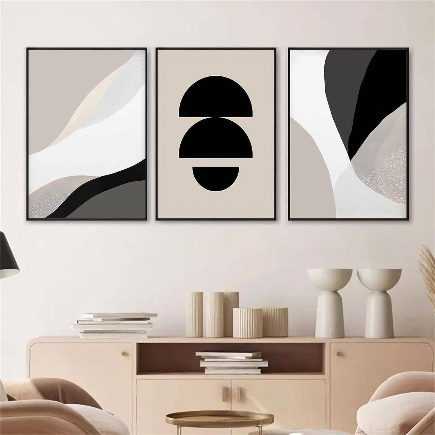 Drei abstrakte Kunstwerke in Schwarz-, Weiß- und Beigetönen hängen an einer Wand über einem modernen Konsolentisch mit minimalistischer Dekoration.