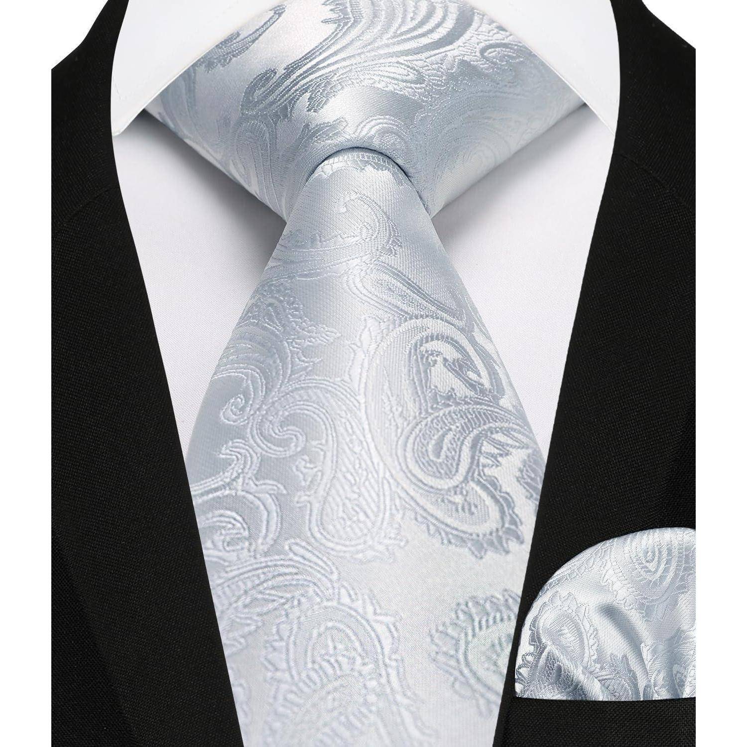 Eine Nahaufnahme eines Anzugs mit einer hellgrauen paisleymusterten Krawatte und einem passenden Einstecktuch, die eine elegante Abendgarderobe zur Schau stellt.