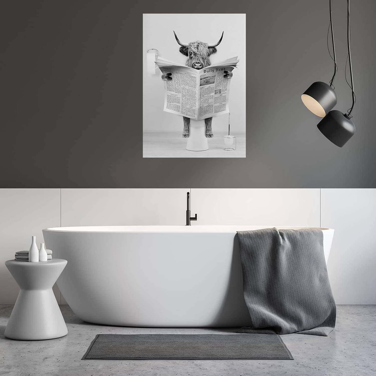 Ein modernes Badezimmer zeigt eine freistehende weiße Badewanne mit einem grauen Handtuch, das über den Rand gehängt ist. Darüber hängt ein humorvolles Foto einer Kuh, die eine Zeitung liest.