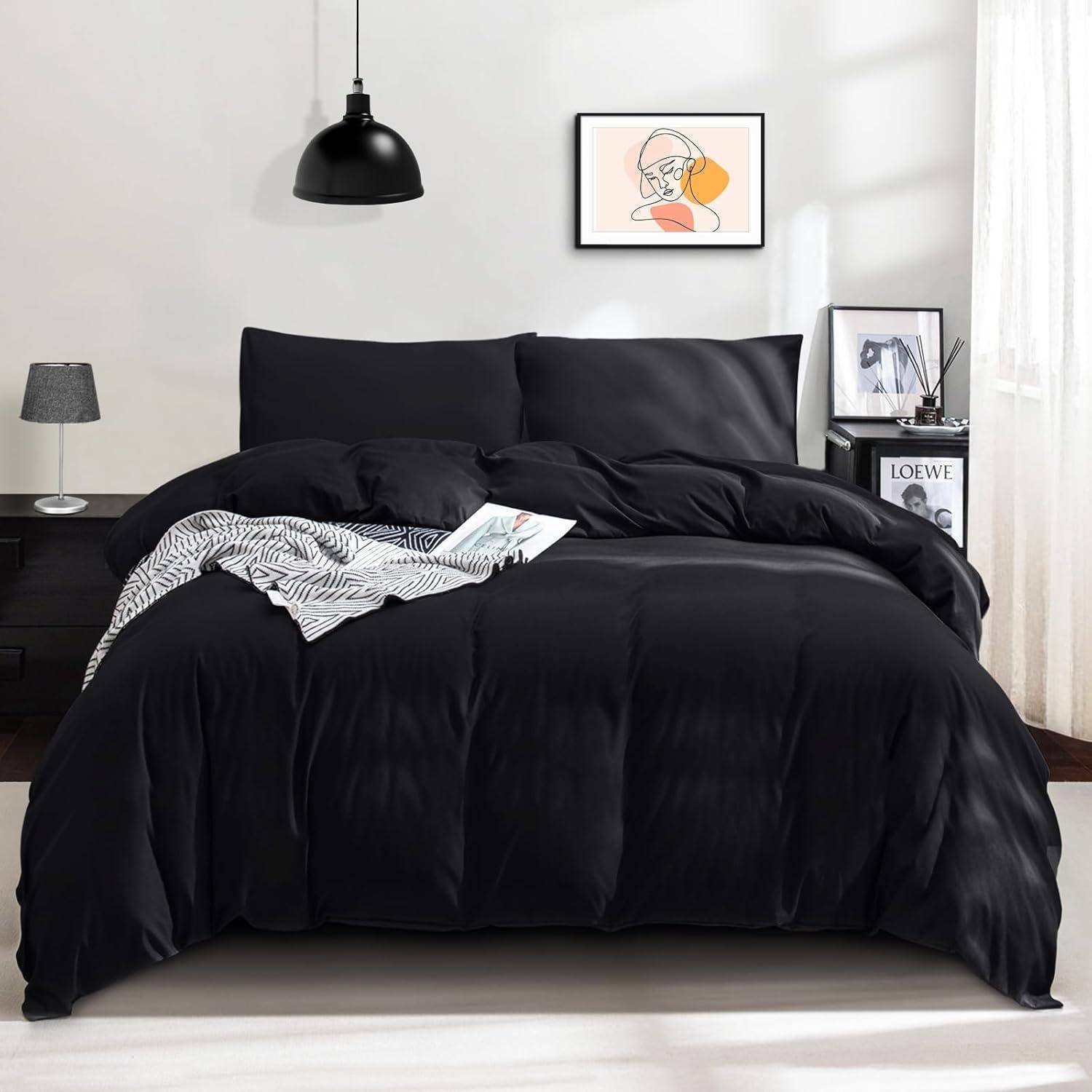 Ein ordentlich gemachtes Bett mit schwarzer Bettwäsche in einem modernen Schlafzimmer; ausgestattet mit zwei Nachttischen mit Lampen und Kunstwerken an der Wand über dem Kopfteil.