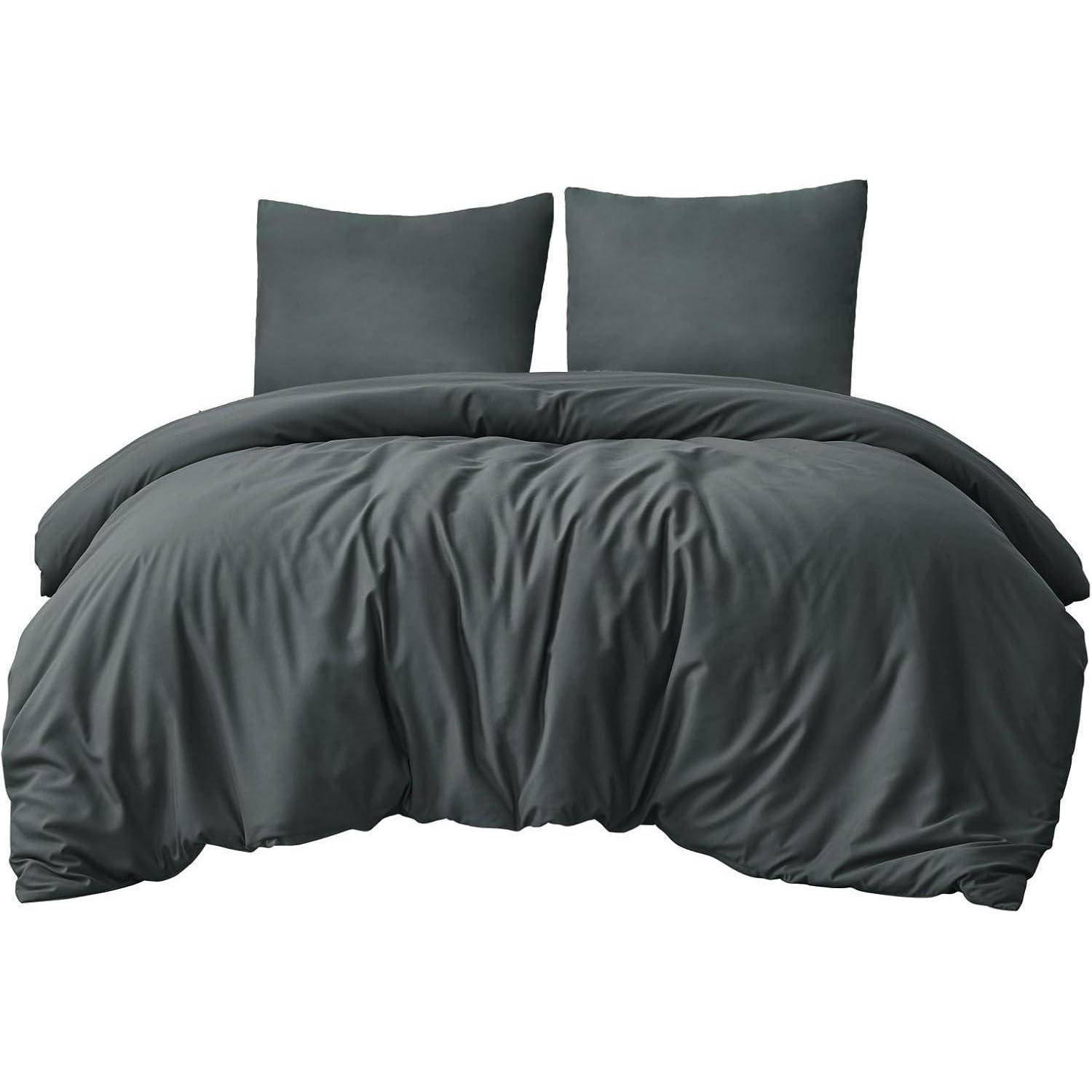 Ein ordentlich gemachtes Bett mit einer dunkelgrauen Bettdecke und zwei passenden Kissen, das einen minimalistischen, modernen Look kreiert.
