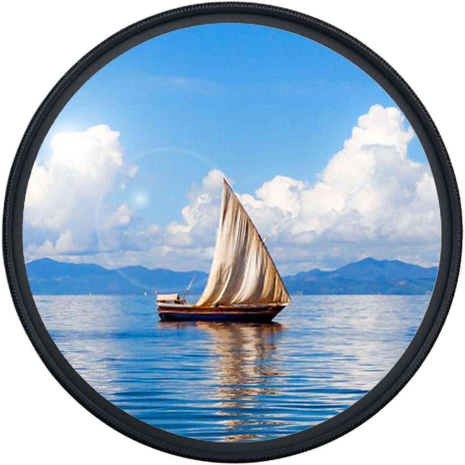 Ein Segelboot mit einem großen weißen Segel gleitet auf ruhigem blauen Wasser unter einem klaren Himmel mit vereinzelten Wolken, umgeben von fernen Bergen.