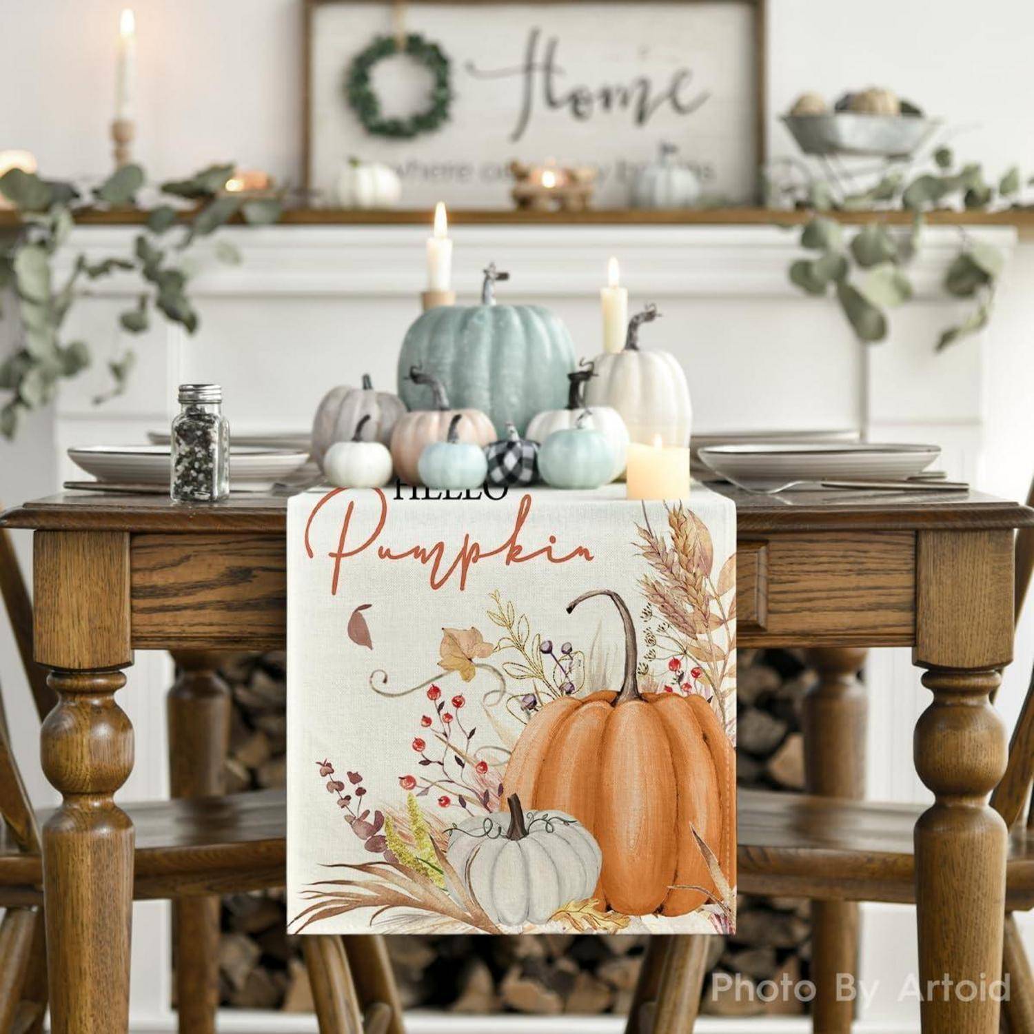 Ein Esstisch ist für den Herbst dekoriert mit einem Tischläufer mit der Aufschrift ‚Hallo Kürbis', der Kürbisse und herbstliches Laub zeigt, in einem gemütlichen Raum.
