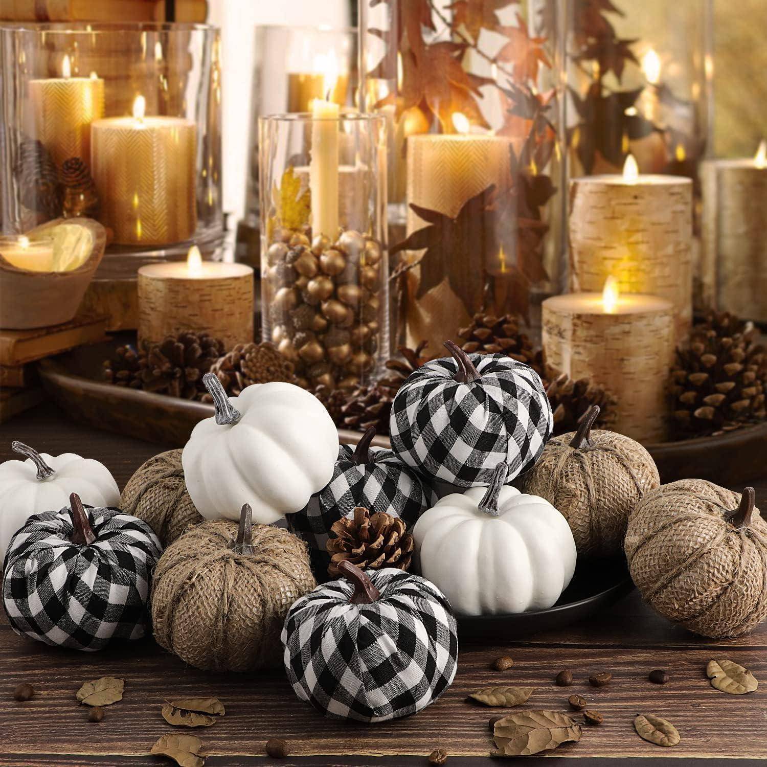 Herbst-Deko-Arrangement mit Kerzen, Tannenzapfen und Kürbissen, teilweise in Karomuster und Jutedesign, auf einem Holztisch.