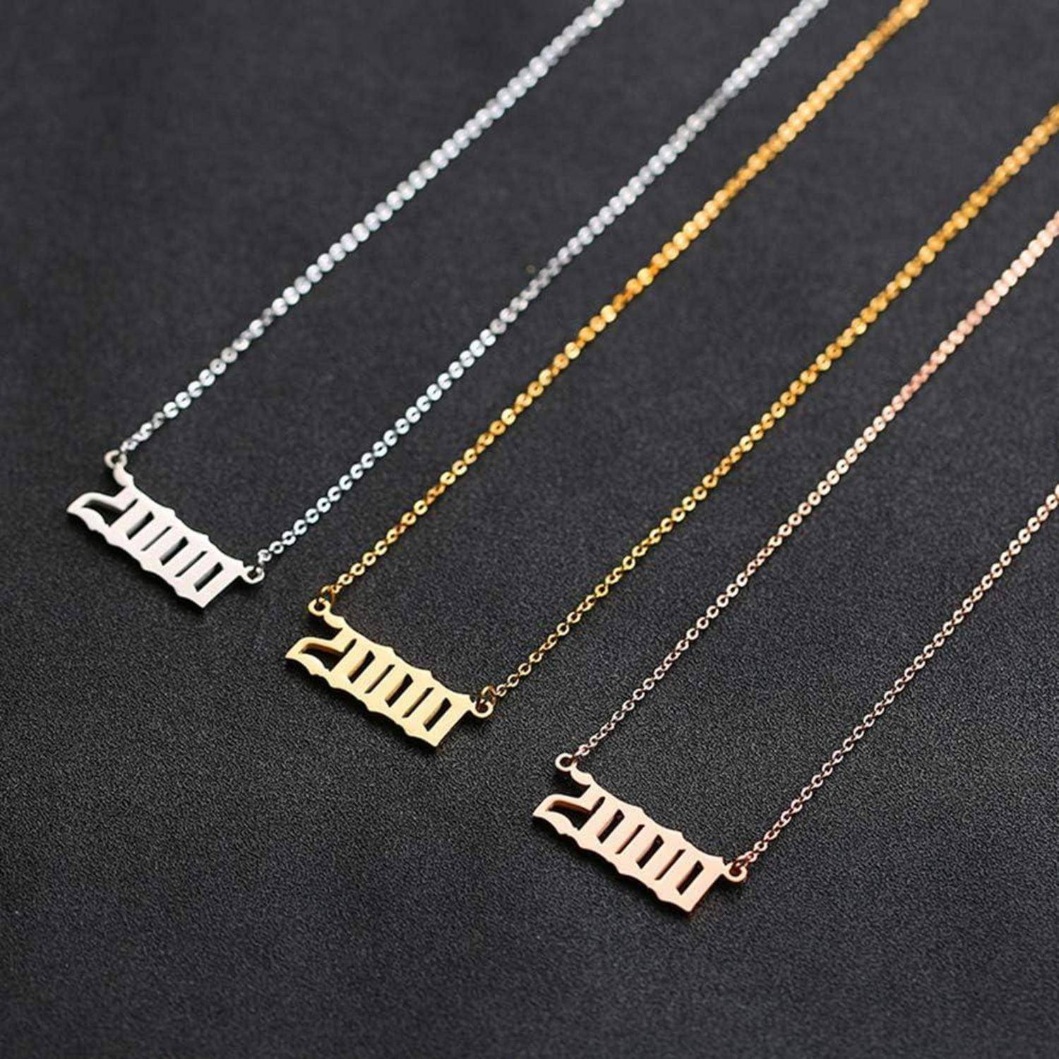 Drei Halsketten auf einer dunklen Oberfläche zeigen Anhänger, die das Wort 'mama' in verschiedenen Ausführungen darstellen: silber, gold und roségold.
