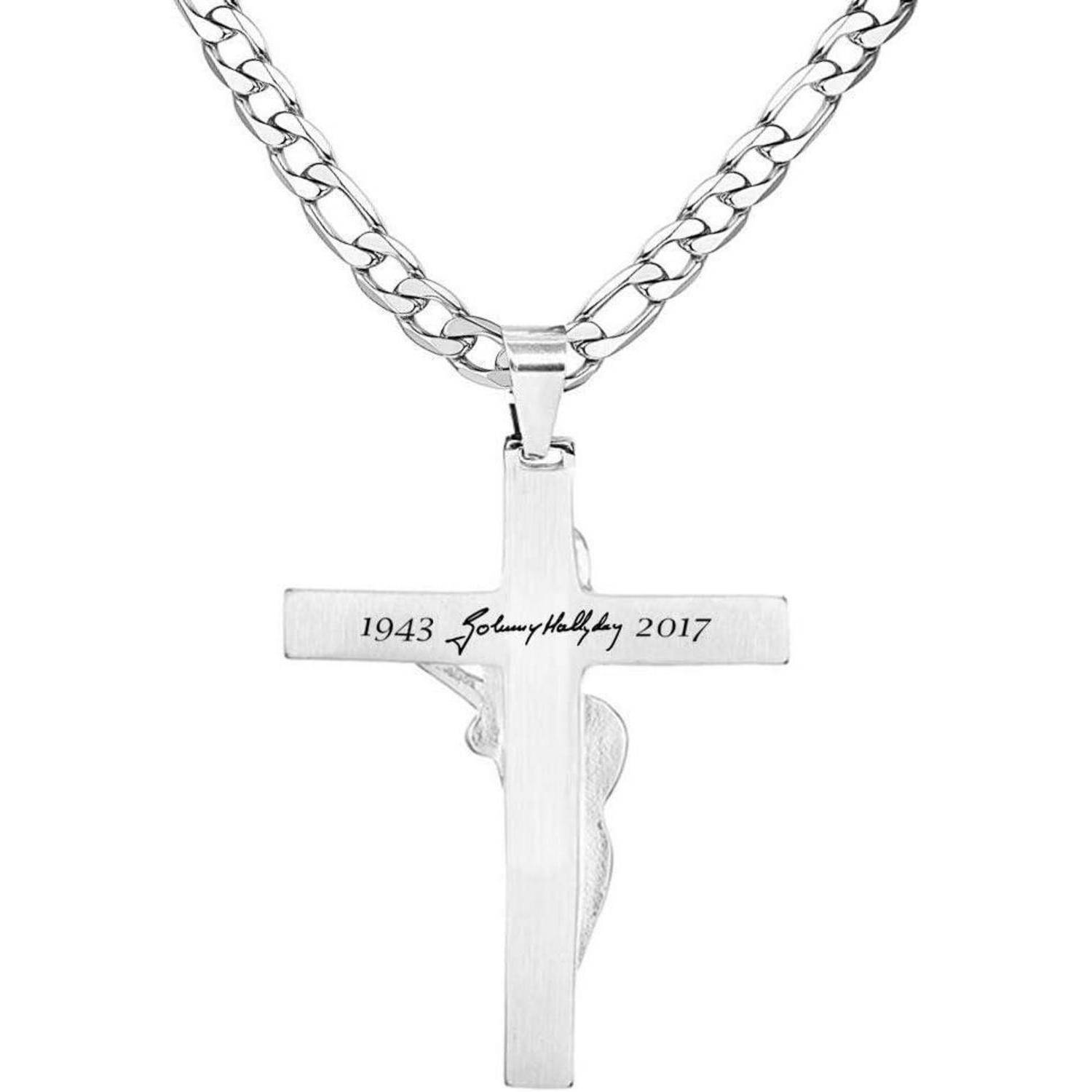 Eine Silberkreuz-Anhänger an einer Kette mit der gravierten Aufschrift '1943 Johnny Hallyday 2017', der als Symbol der Erinnerung dient.