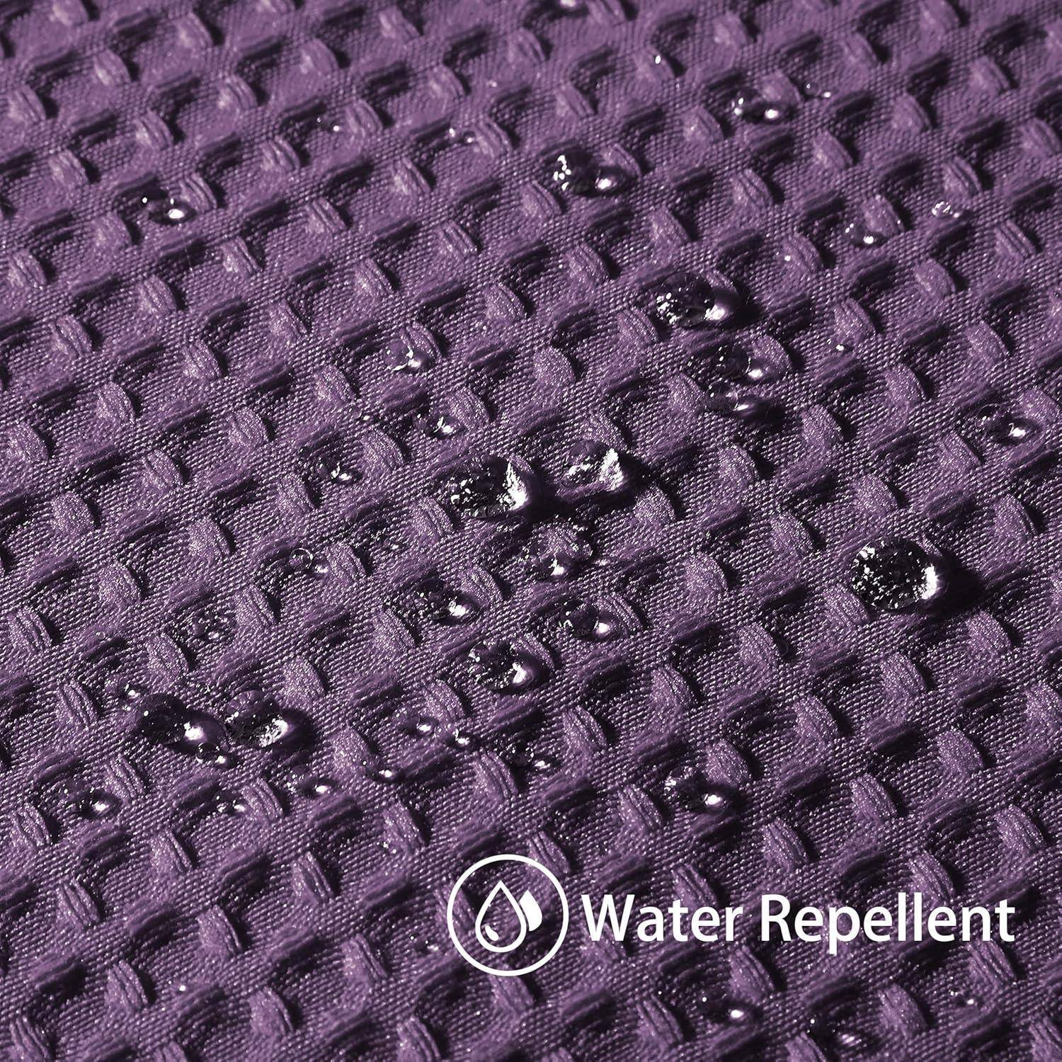 Wassertropfen perlen auf einer lila strukturierten Stoffoberfläche auf und zeigen dessen wasserabweisende Eigenschaft. Der Text lautet „Wasserabweisend