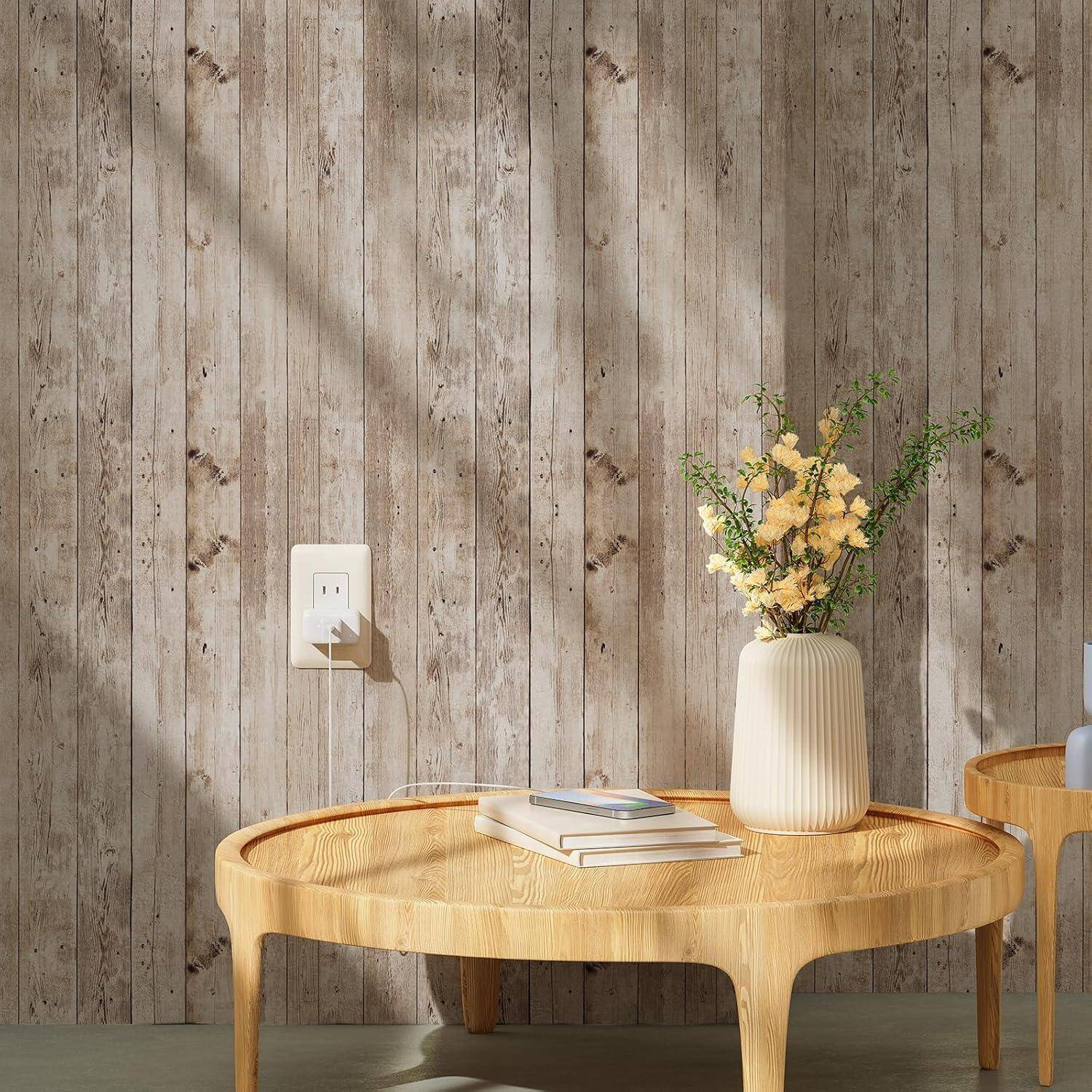 Ein leichter Holz-Couchtisch trägt eine Vase mit gelben Blumen und gestapelten Büchern. Der Hintergrund zeigt eine rustikale, mit Holzpaneelen verkleidete Wand.