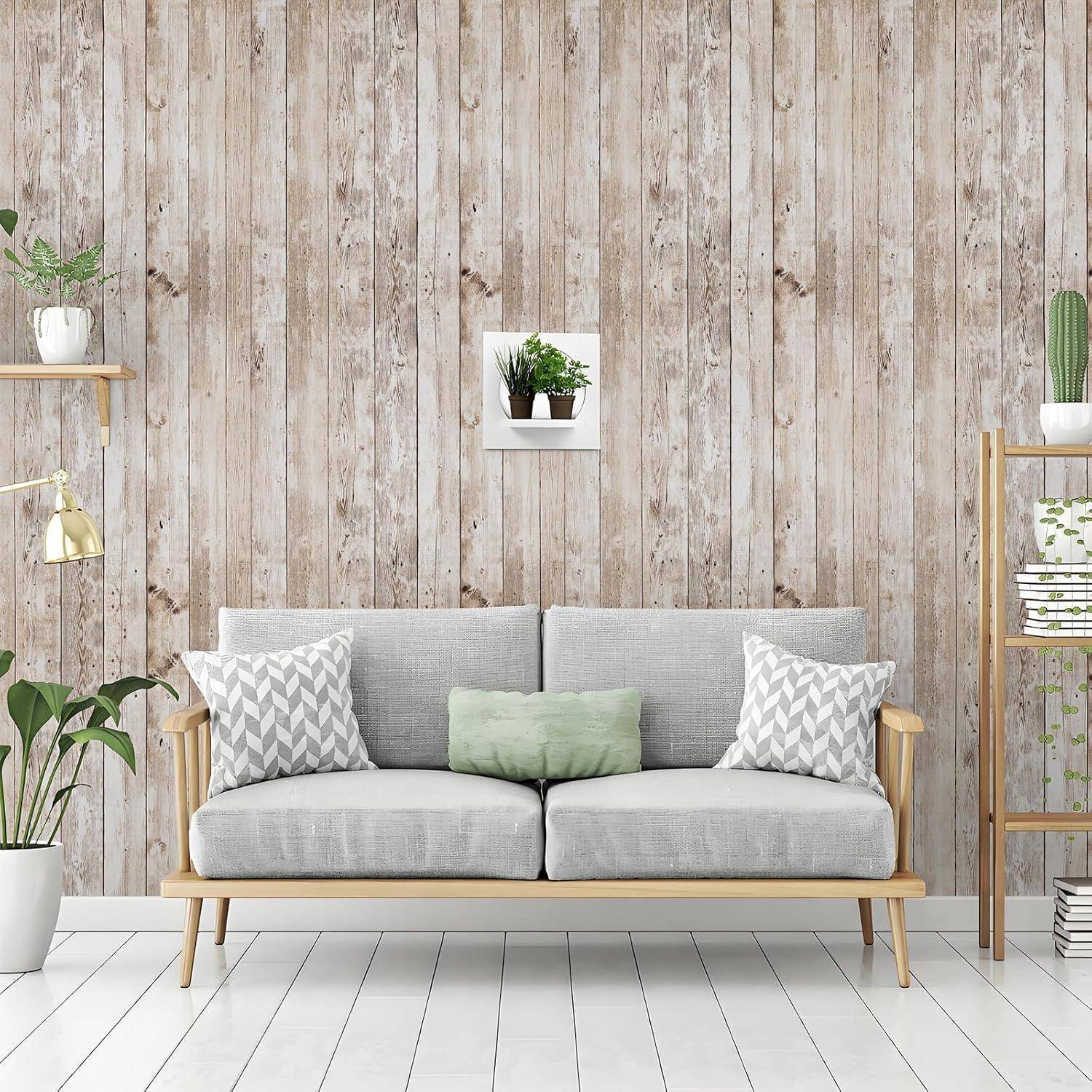 Ein stilvolles Wohnzimmer mit einem hellgrauen Sofa mit gemusterten Kissen vor einer Holzlamellenwand, mit Topfpflanzen und Bücherregalen.