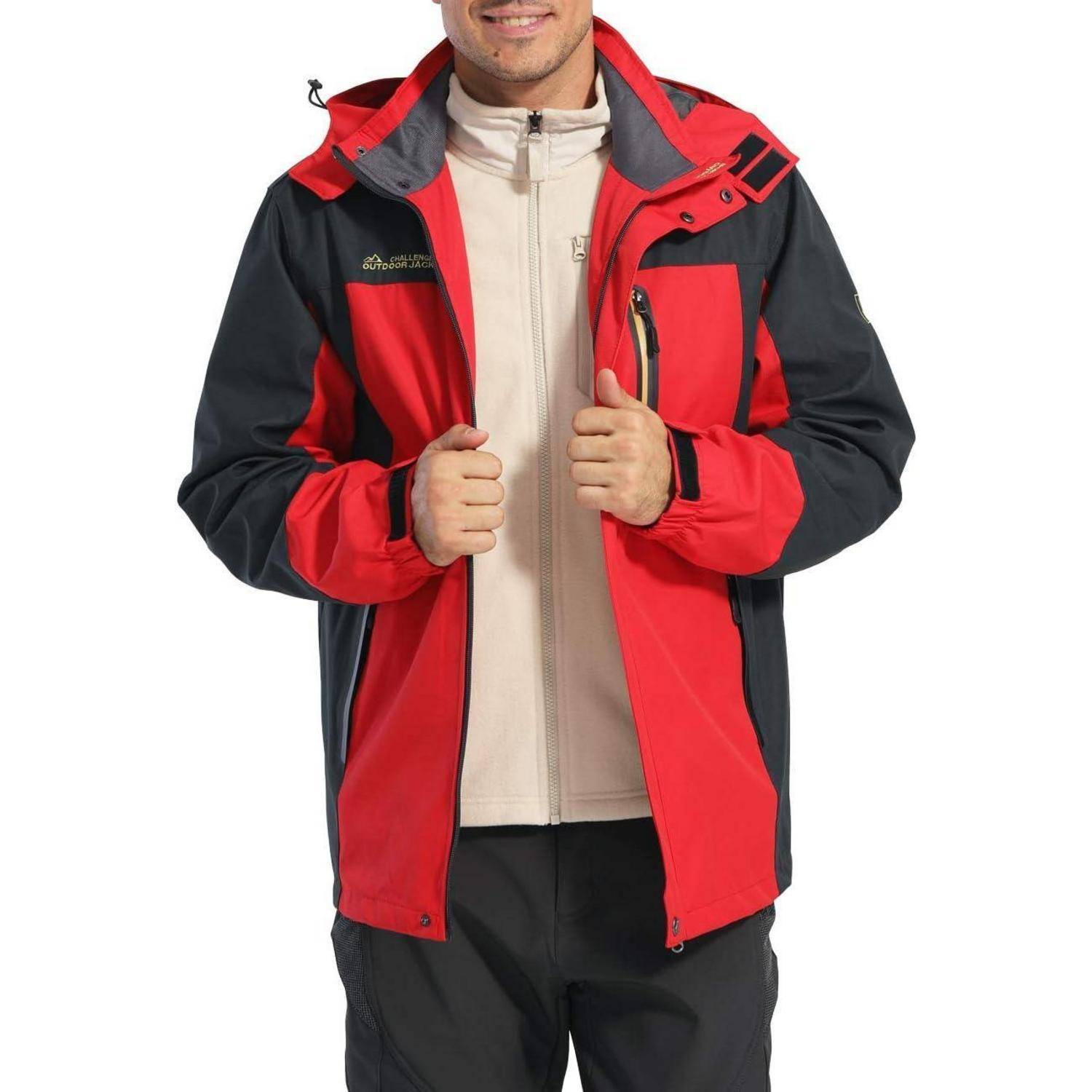 Eine Person trägt eine rote und schwarze Outdoor-Jacke über einem beigen Reißverschluss-Pullover und hält die Jacke mit einer Hand offen.