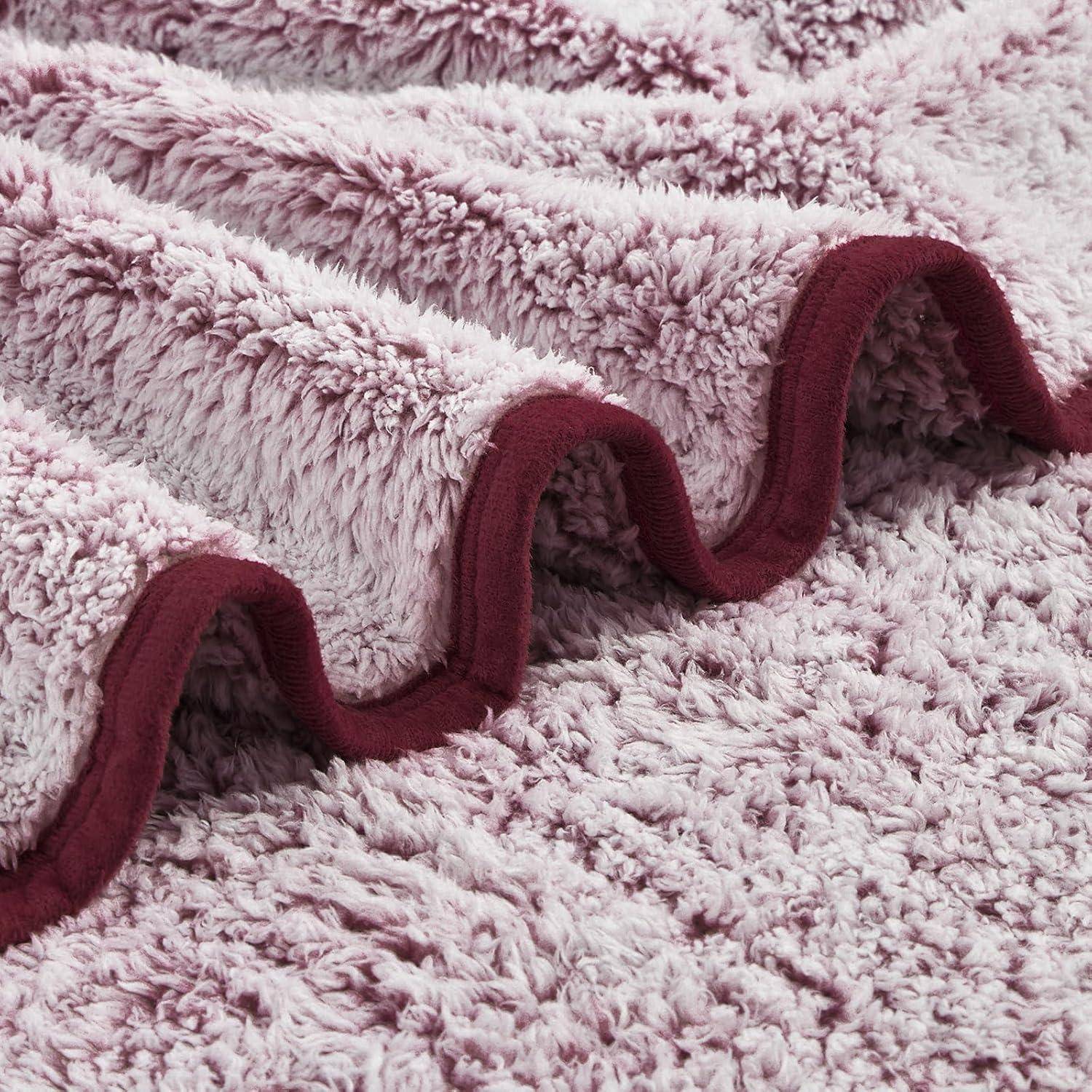 Eine Nahaufnahme einer weichen, flauschigen Fleecdecke in Rosa und Burgunderrot, die deren Textur und wellenförmige Falten zeigt.