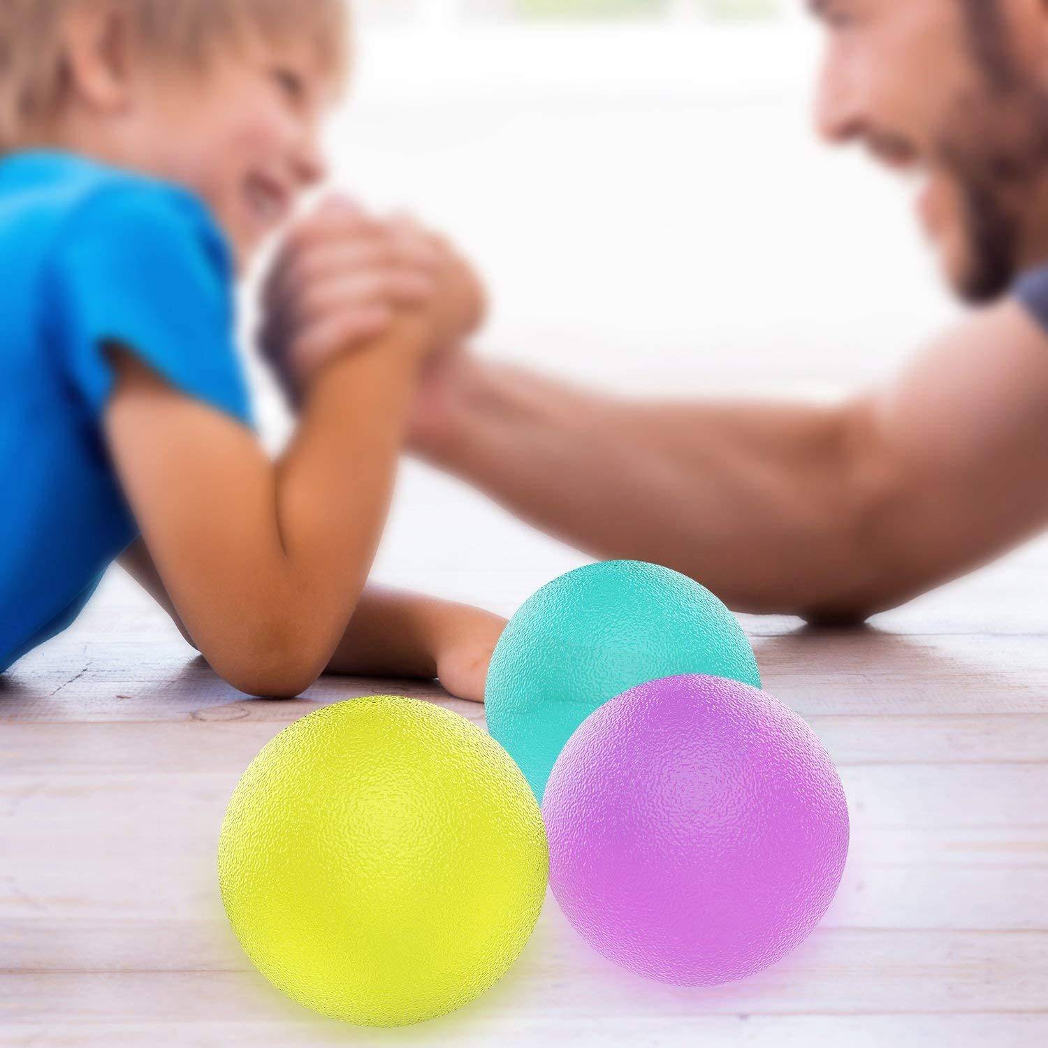 Ein Kind und ein Erwachsener ringen spielerisch auf einem Holzboden neben bunten Gummibällen in Blau, Lila und Gelb.