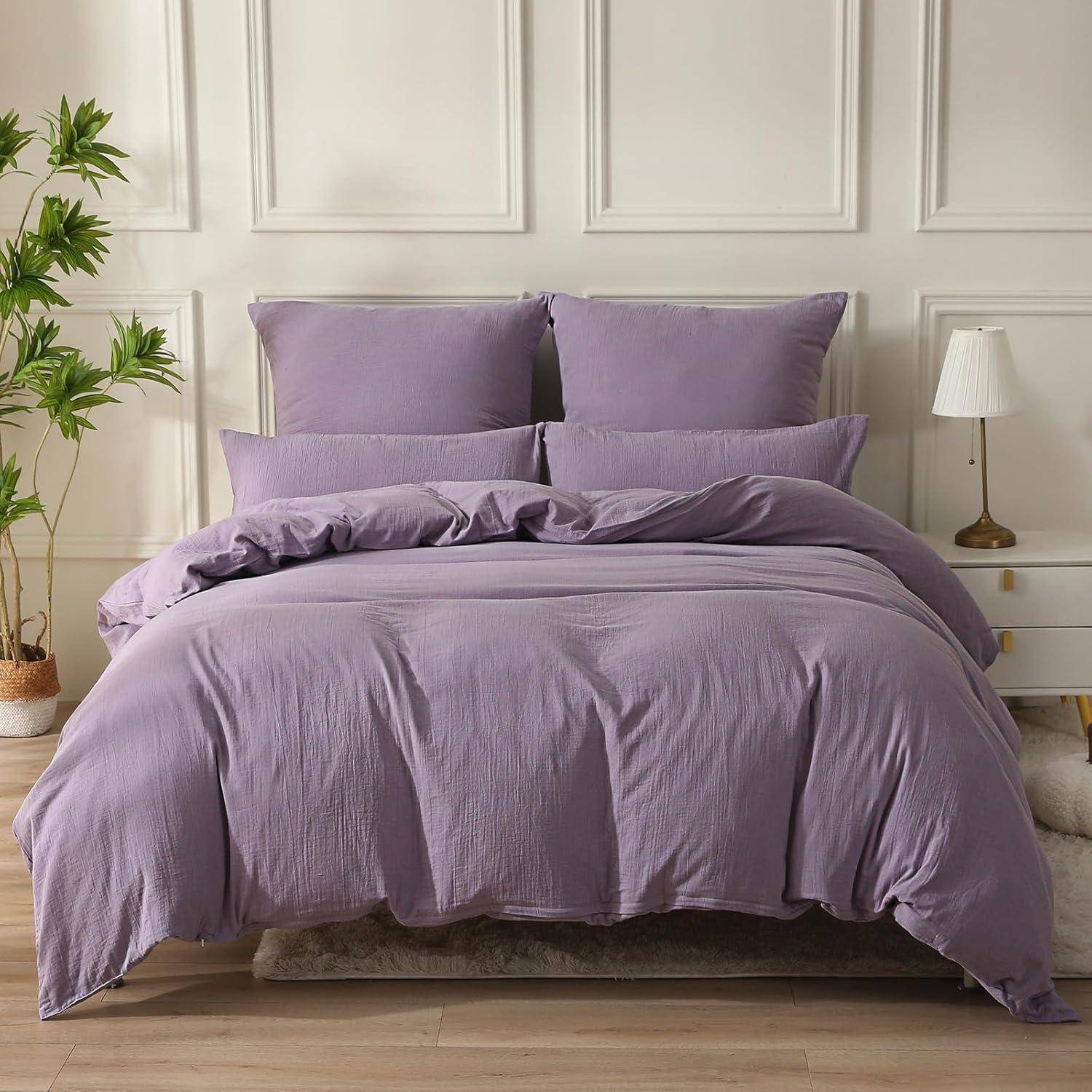 Ein ordentlich gemachtes Bett mit Lavendelbettwäsche und -kissen, aufgestellt in einem hellen Raum mit einer Zimmerpflanze und einer Lampe, die eine gemütliche Atmosphäre schaffen.