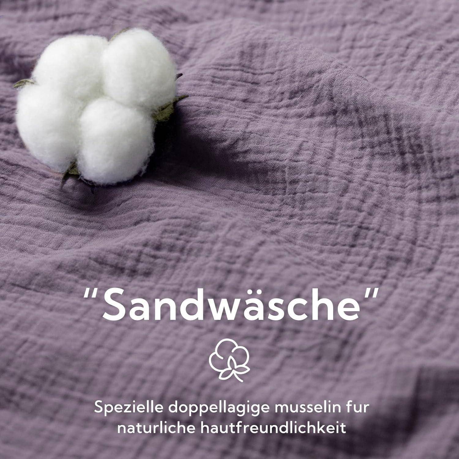 Eine Baumwollpflanze vor einem texturierten Stoffhintergrund mit dem Text 'Sandwäsche' und 'Spezielle doppellagige Musselin für natürliche Hautfreundlichkeit'.