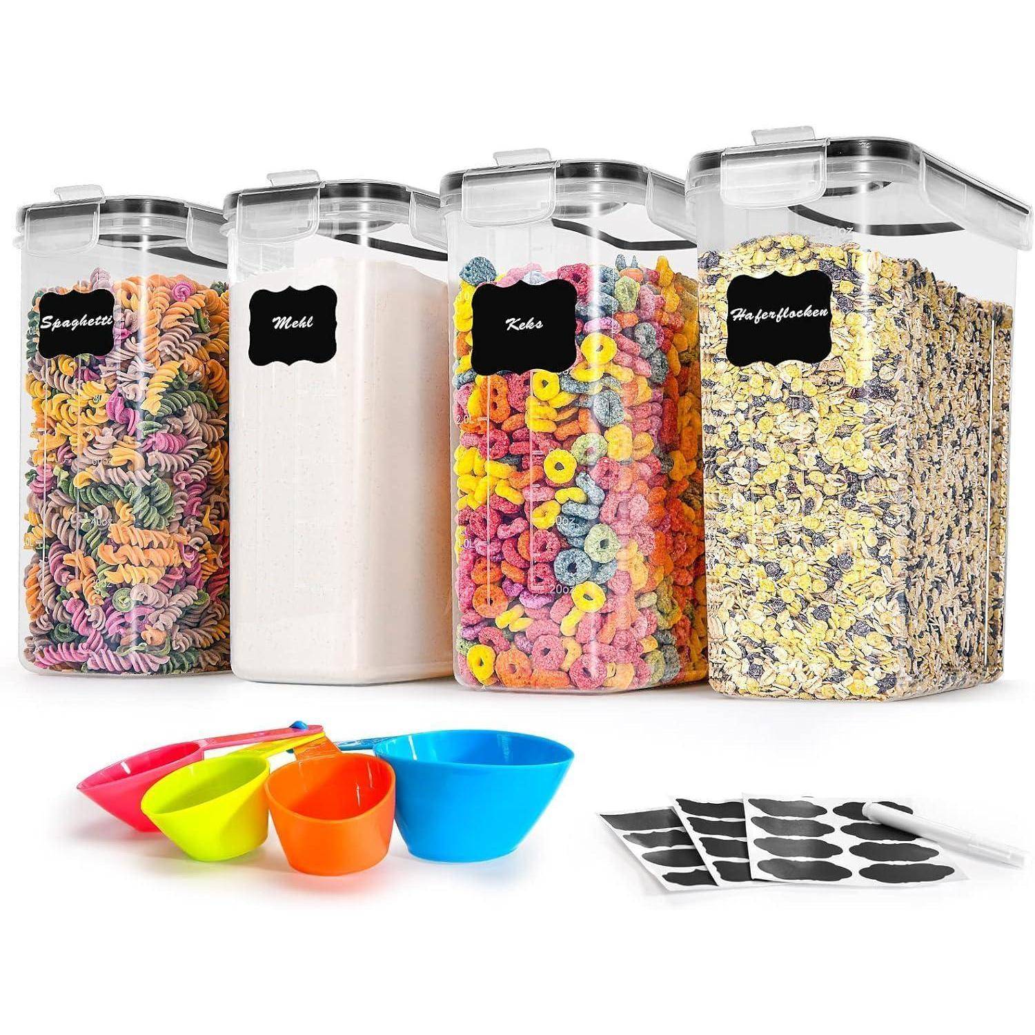 Vier durchsichtige Behälter, beschriftet mit 'Spaghetti', 'Mehl', 'Kekse' und 'Haferflocken', enthalten Nudeln, Mehl, Müsli und Haferflocken. Bunte Messbecher und Etiketten befinden sich davor.