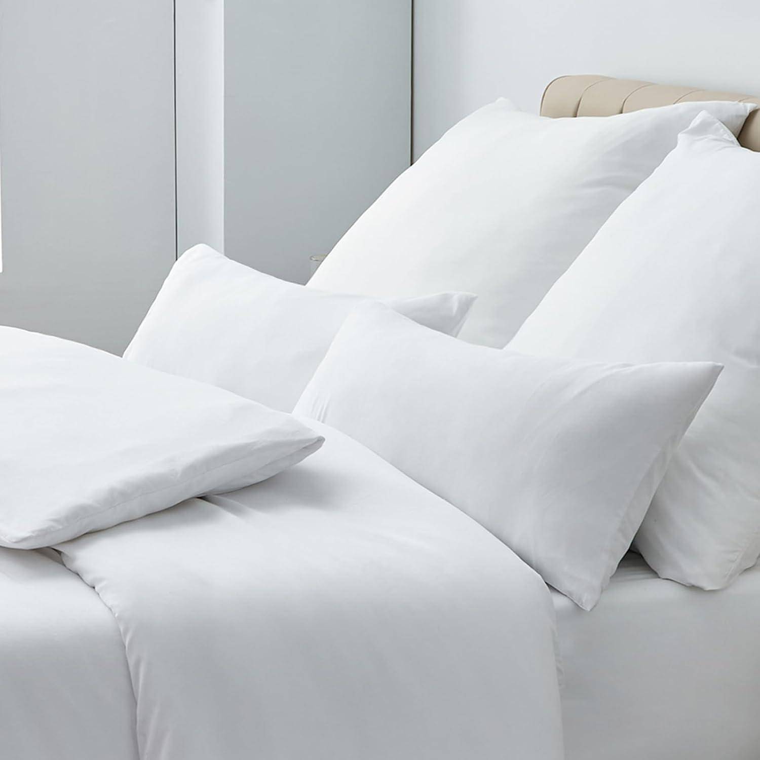Ein ordentlich gemachtes Bett mit weißen Laken, Kissen und einer gesteppten Kopfstütze, das ein Gefühl von Sauberkeit und Behaglichkeit vermittelt.