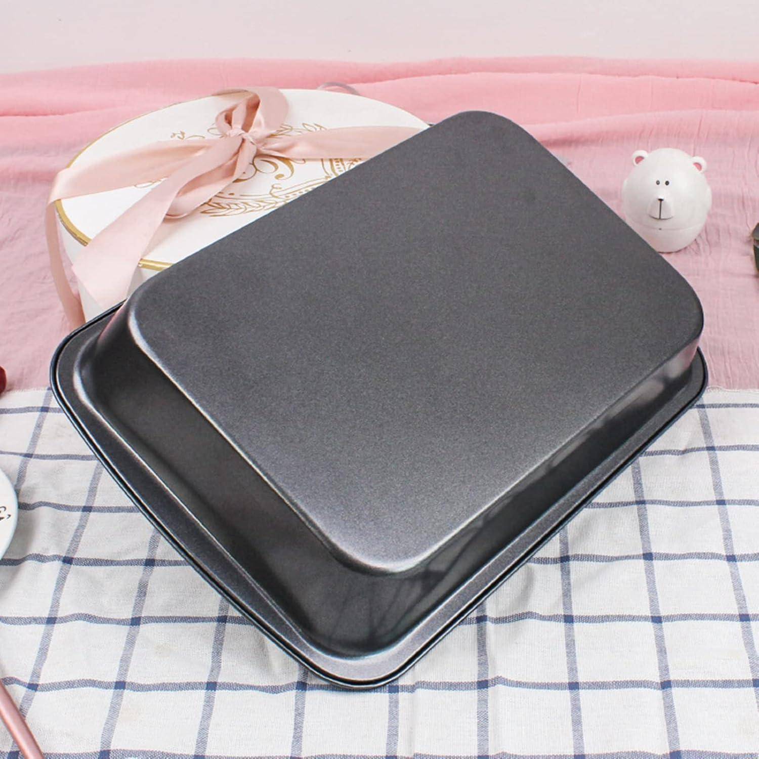 Ein schwarzes Backblech steht auf einem karierten Tuch mit Dekorationsgegenständen, darunter eine Keramikbärfigur und eine runde Geschenkbox im Hintergrund.