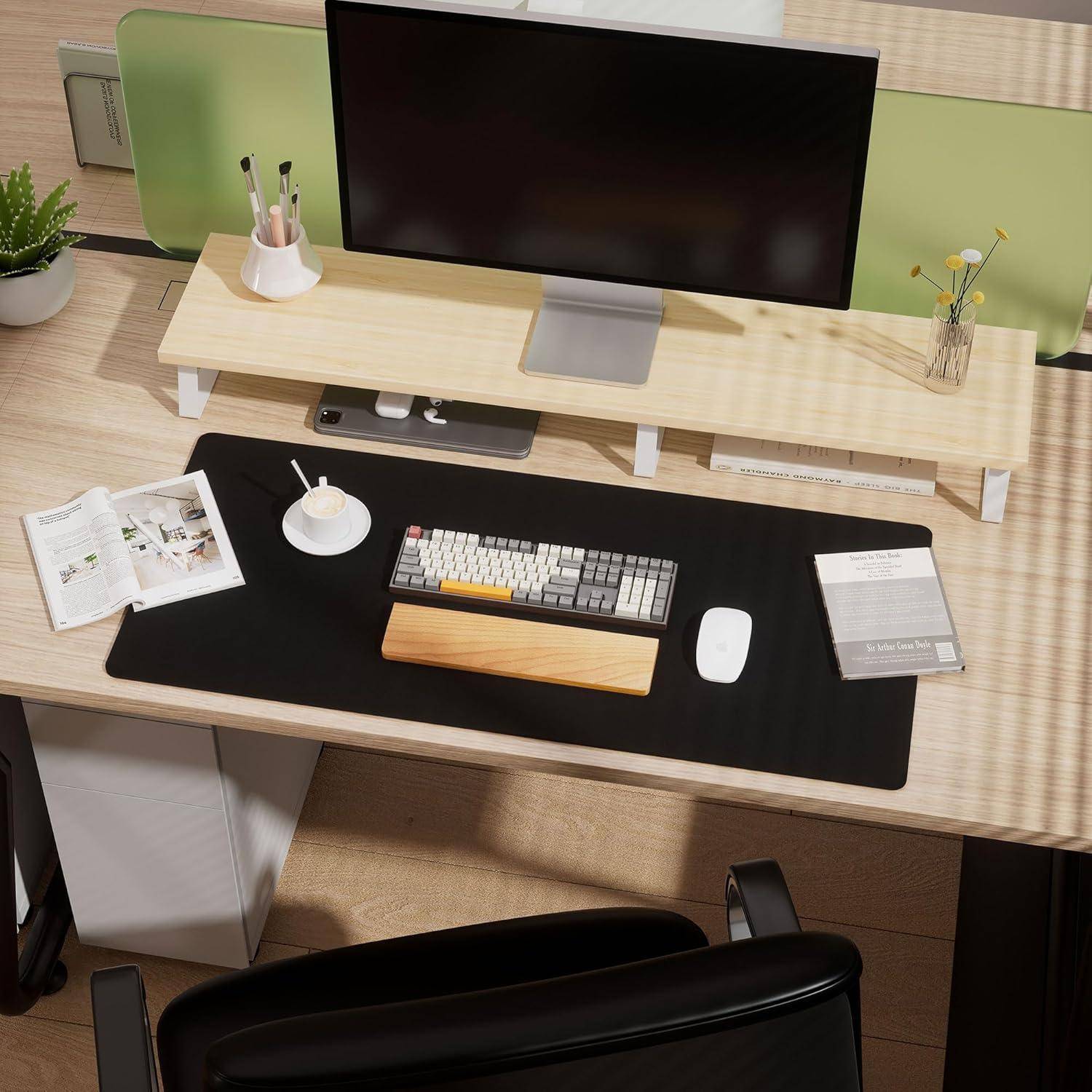 Ein aufgeräumter Arbeitsplatz mit einem Computermonitor auf einem Holzschreibtisch, Tastatur, Maus, Pflanze und Büchern, was auf eine saubere, organisierte Umgebung hindeutet.