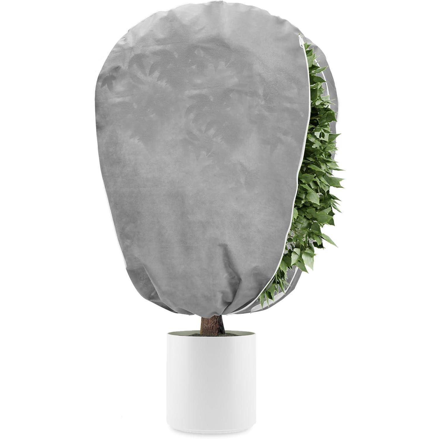 Ein Baum in einem weißen Topf ist teilweise von einer grauen Schutzabdeckung verdeckt, wobei auf einer Seite grüne Blätter sichtbar sind.