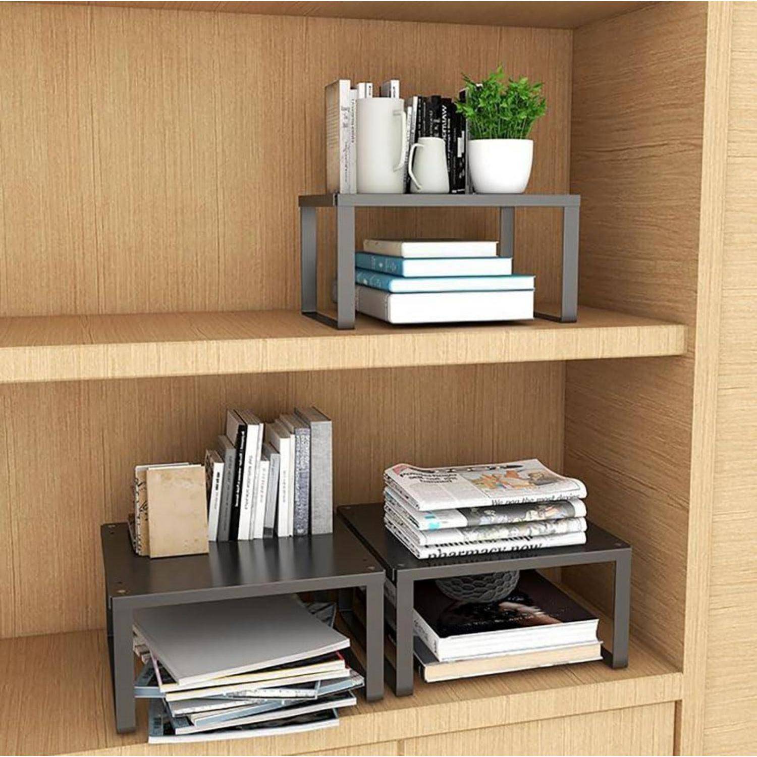 Zwei Holzregale mit Metalleinfassungen tragen Stapel von Büchern, Notizbüchern, eine Kaffeetasse und eine Topfpflanze.
