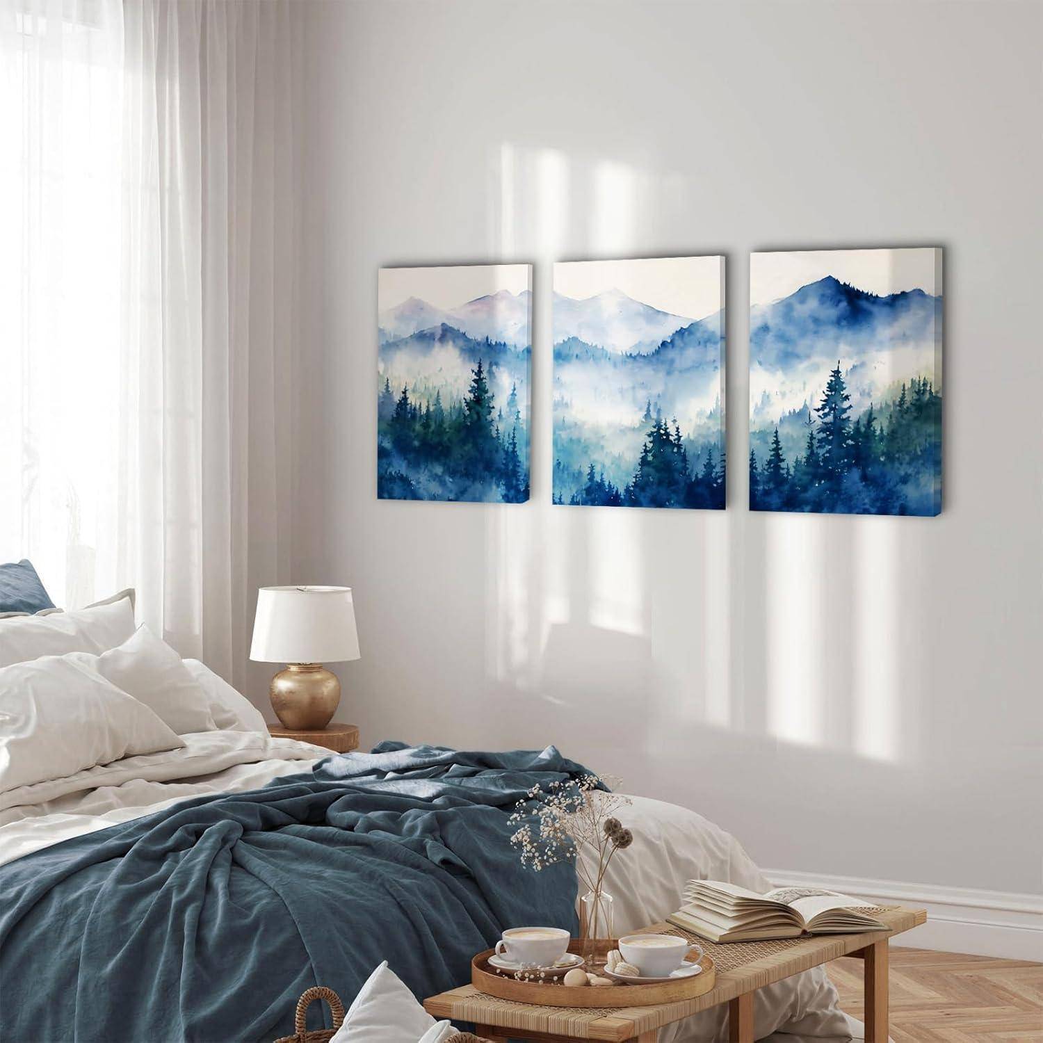 Ein gemütliches Schlafzimmer zeigt ein Bett mit grauer Bettwäsche, einer weißen Lampe und einem Holznachttisch. Drei Berglandschaftsgemälde hängen an der Wand.