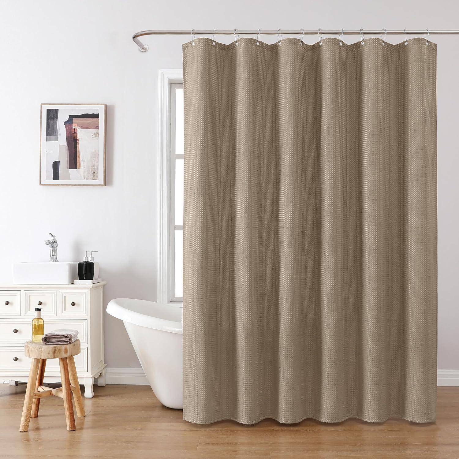 Ein modernes Badezimmer mit einem beigen Duschvorhang, einer weißen freistehenden Badewanne und einem Waschbecken. Ein kleiner Holzhocker trägt Toilettenartikel.