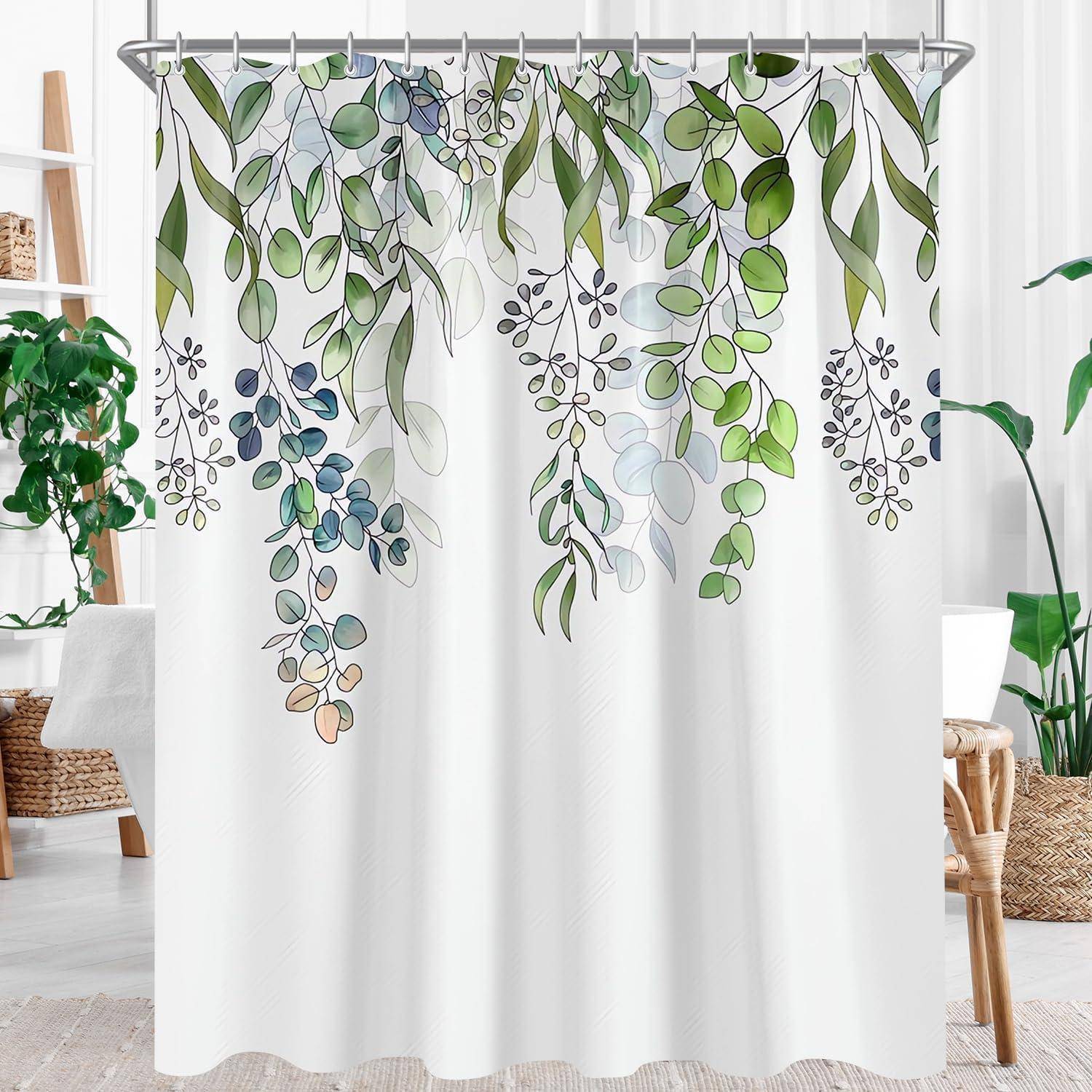 Duschvorhang mit botanischem Design, auf dem hängende grüne und blaue Blätterzweige abgebildet sind, in einem hellen Badezimmer mit Rattanakzenten.